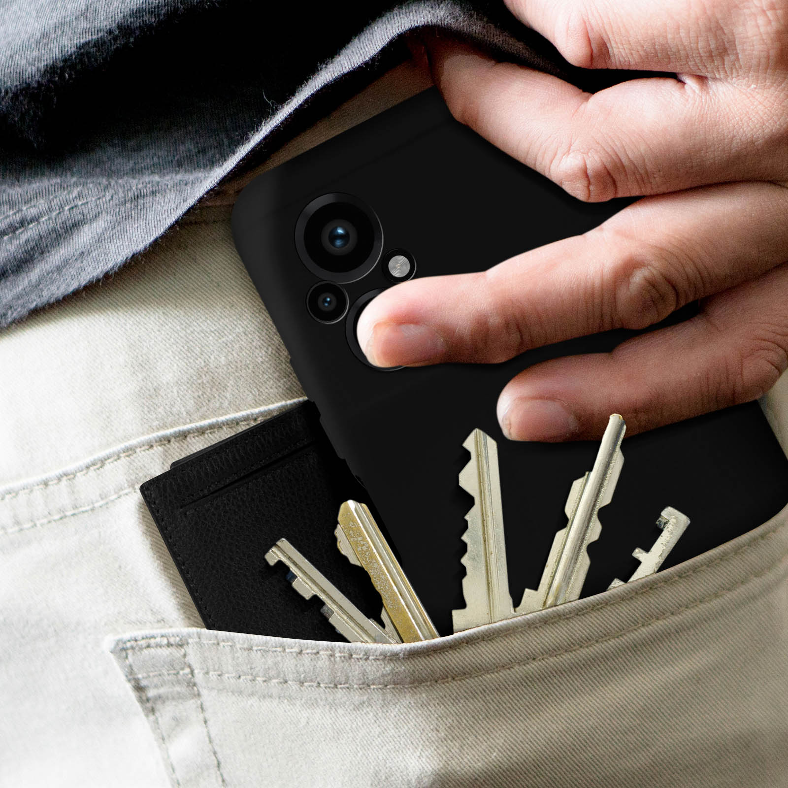 Hand hält ein schwarzes Telefon in einer Tasche mit Schlüsseln und Geldbörse.