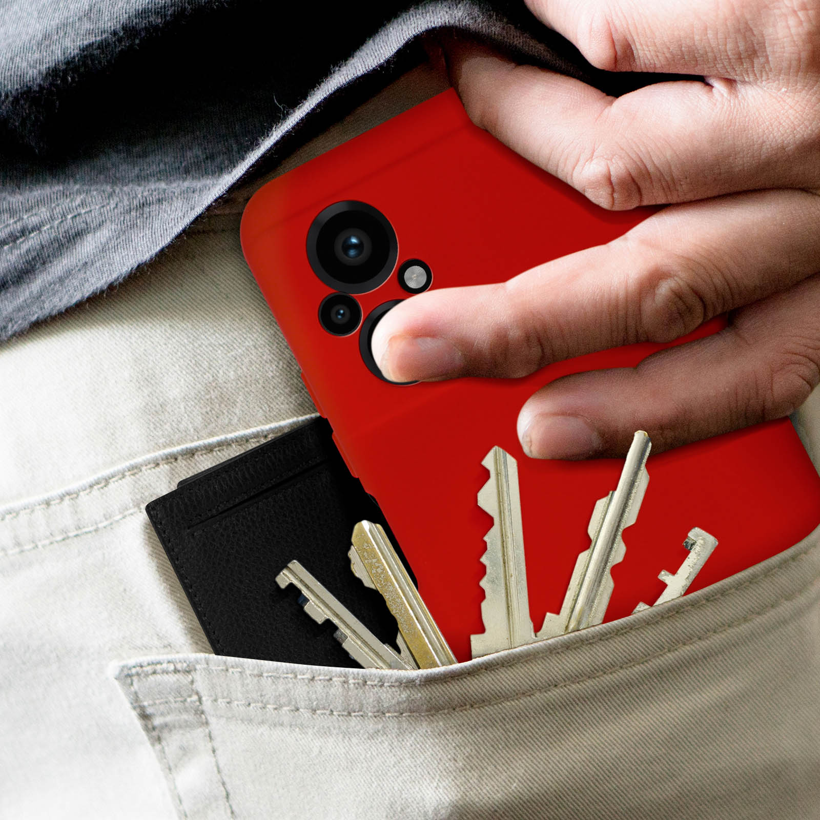 Hand in Tasche mit rotem Telefon. Schlüssel und schwarzes Portemonnaie ebenfalls in der Tasche.