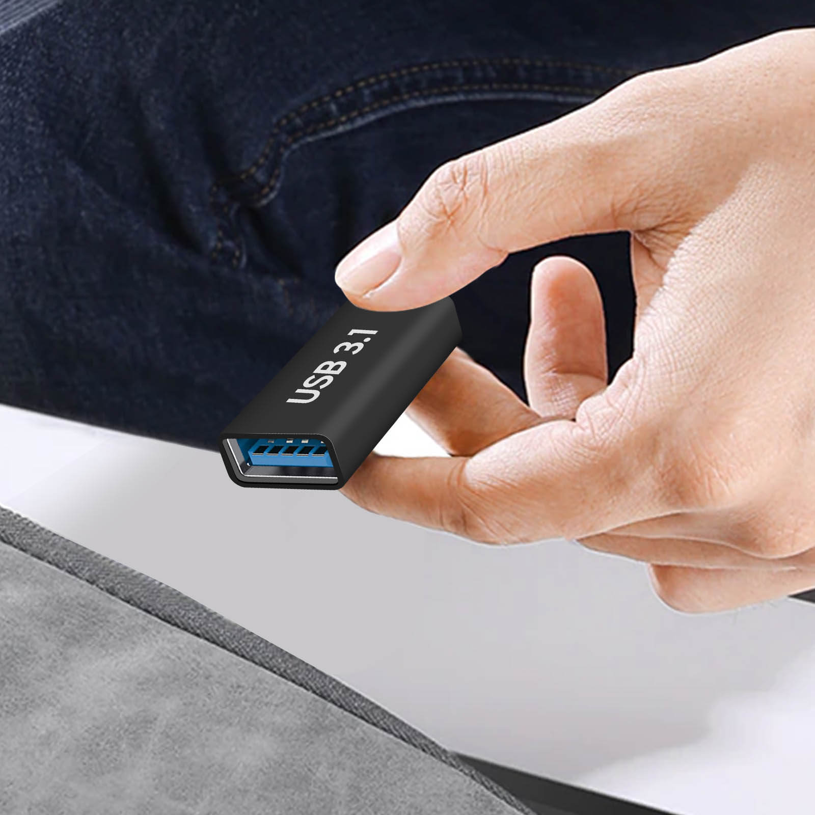 Una mano che tiene un'unità USB 3.1 nera. L'unità ha un connettore blu sopra una superficie.