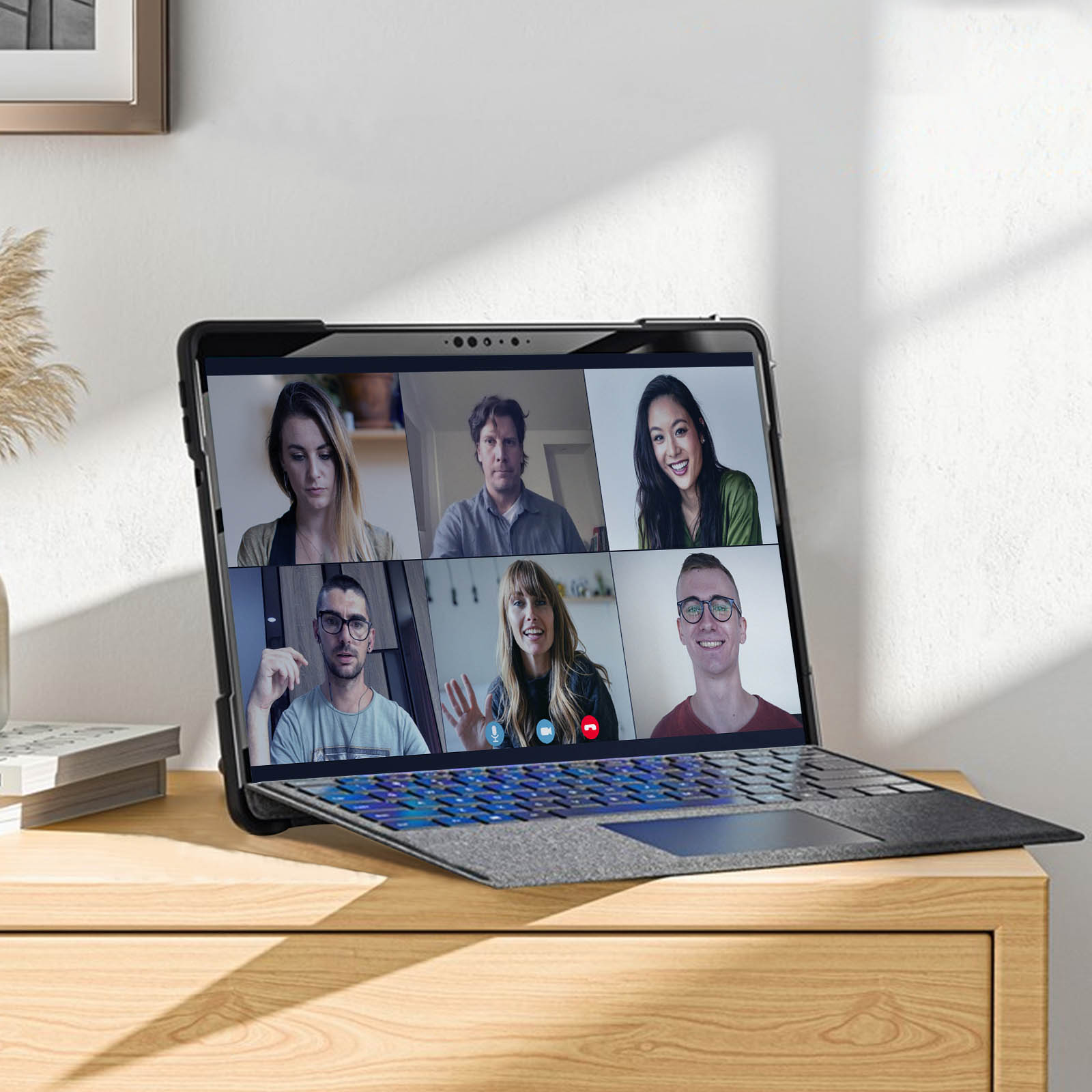 Laptop zeigt eine Videokonferenz. Sechs Personen auf dem Bildschirm. Laptop auf einem Holzschreibtisch.