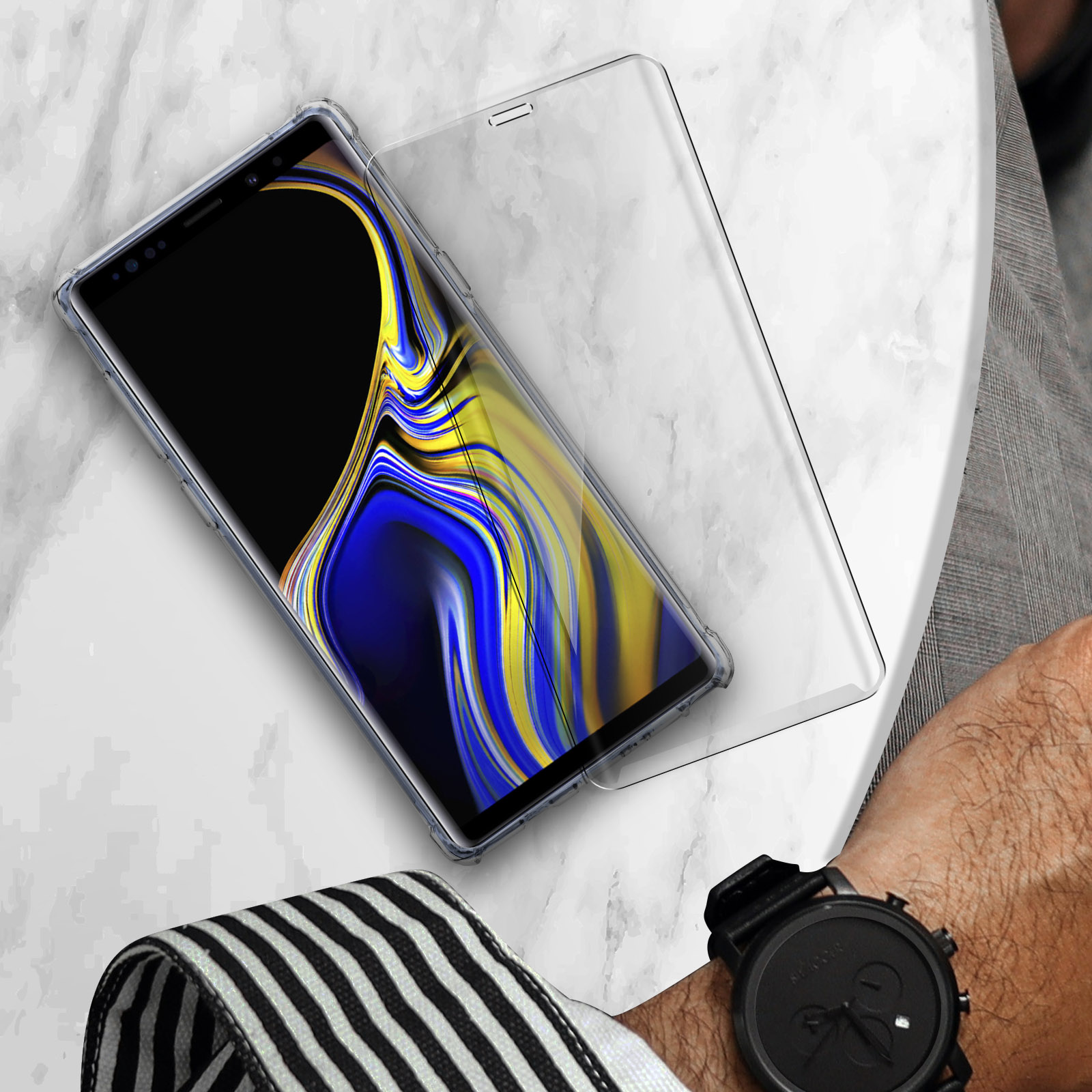Un telefono protetto da una protezione per lo schermo è posto su una superficie di marmo con un orologio.