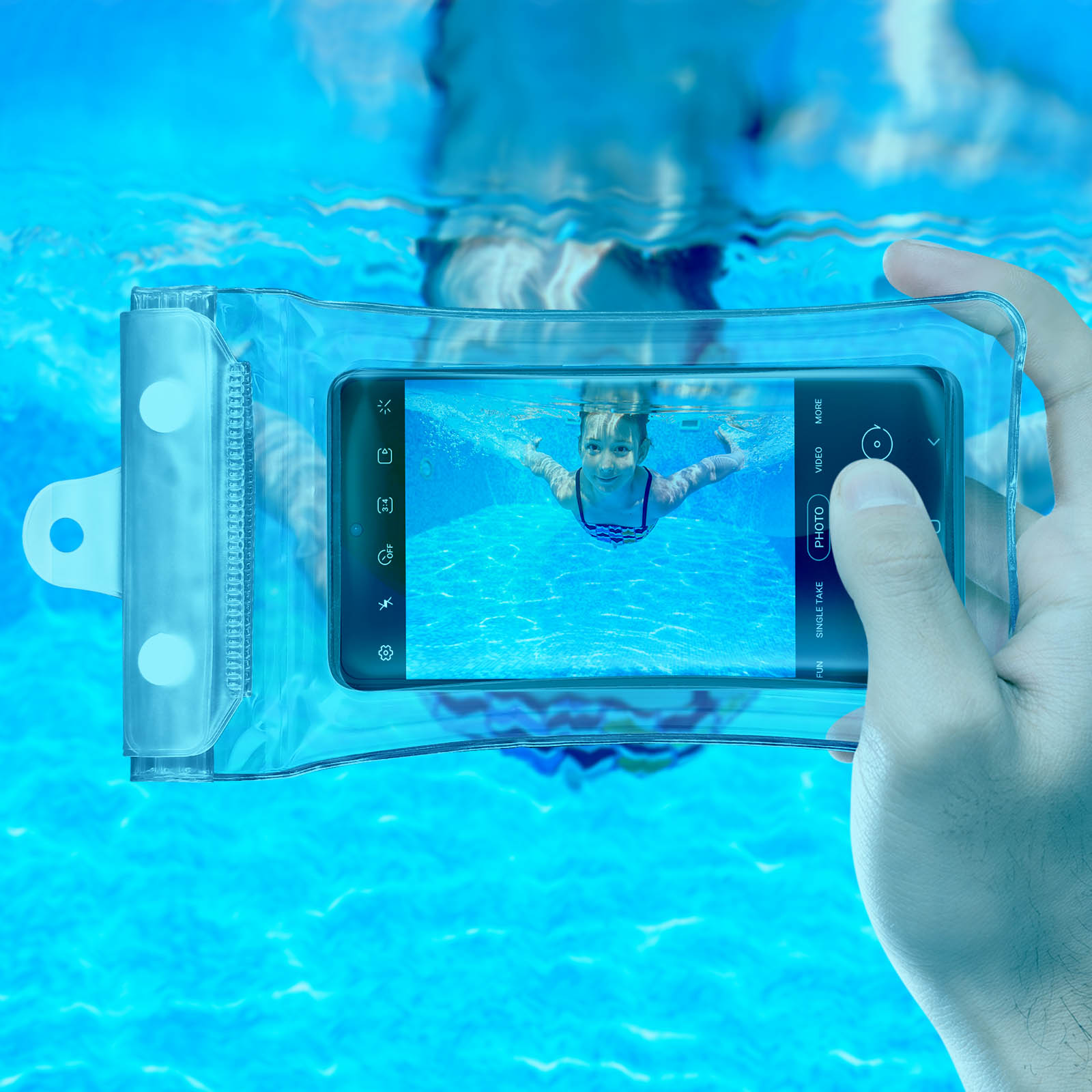 Eine Person hält ein Telefon in einer wasserdichten Hülle unter Wasser. Ein Mädchen schwimmt.