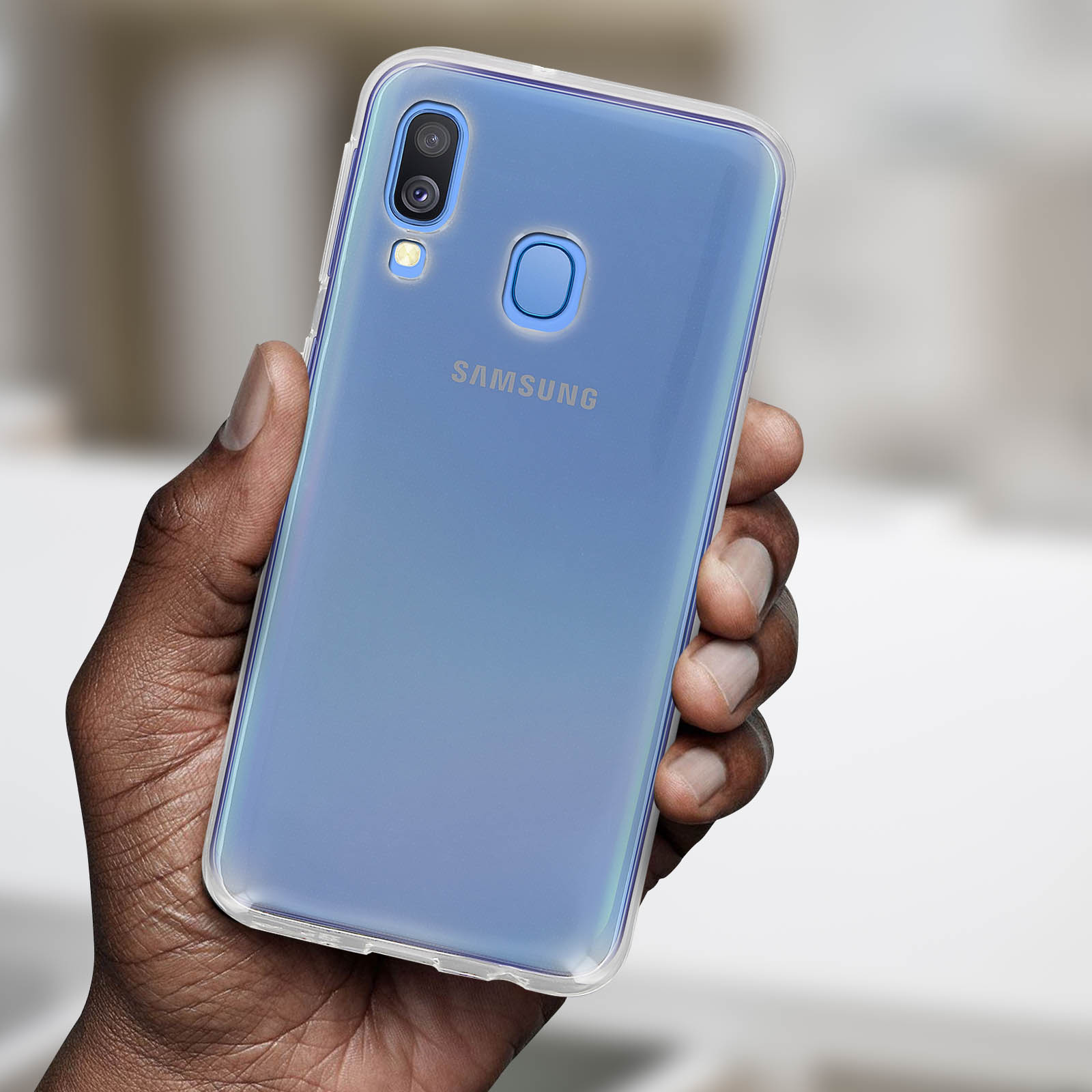 Een hand die een Samsung-telefoon vasthoudt met een doorzichtige beschermhoes. De telefoon heeft een blauwe achterkant.