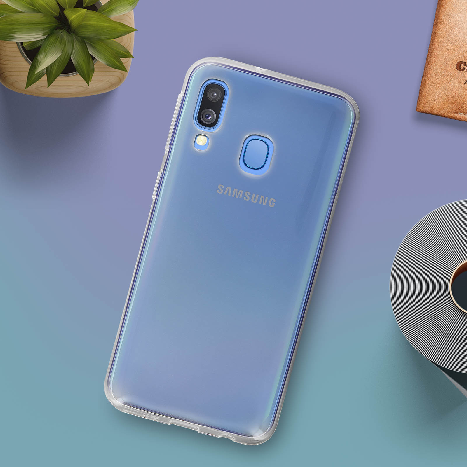 Telefoonhoesje op een tafel. Blauwe telefoon met een doorzichtig telefoonhoesje. Plant en andere objecten op de achtergrond.