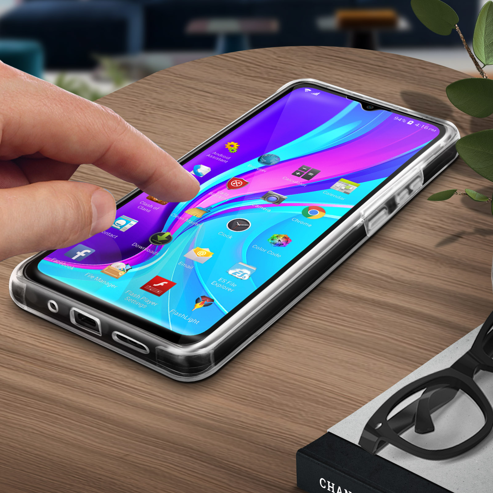 Téléphone dans un étui transparent, main touchant l'écran. Icônes d'applications affichées. Lunettes noires et plante en arrière-plan.