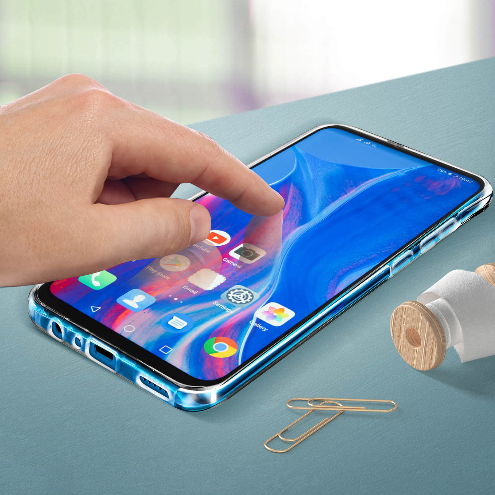 Main touchant l'écran du téléphone. Téléphone avec coque transparente. Trombones à côté.