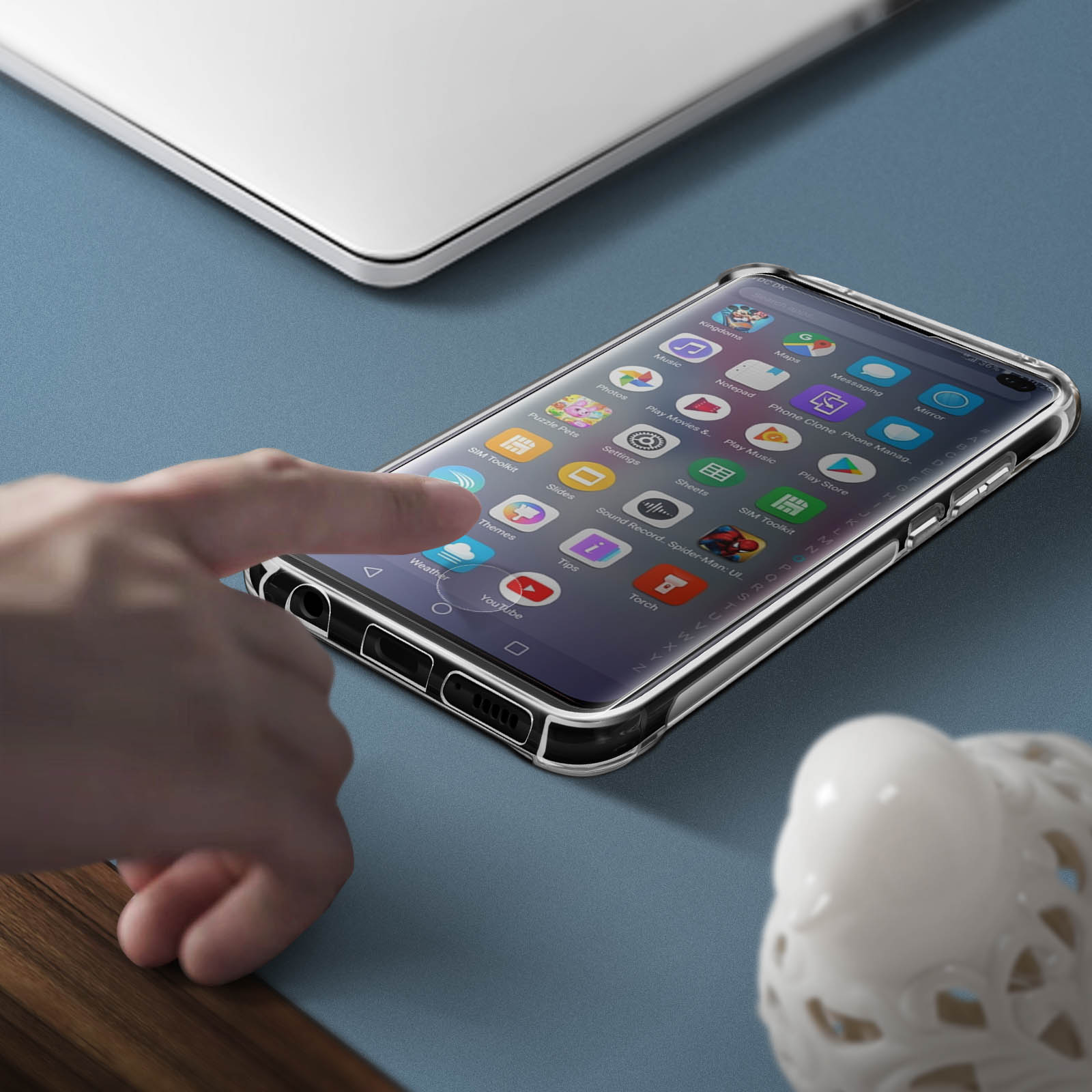 Ein Smartphone in einer durchsichtigen Hülle, mit einer Hand, die den Bildschirm berührt, auf blauer Fläche.