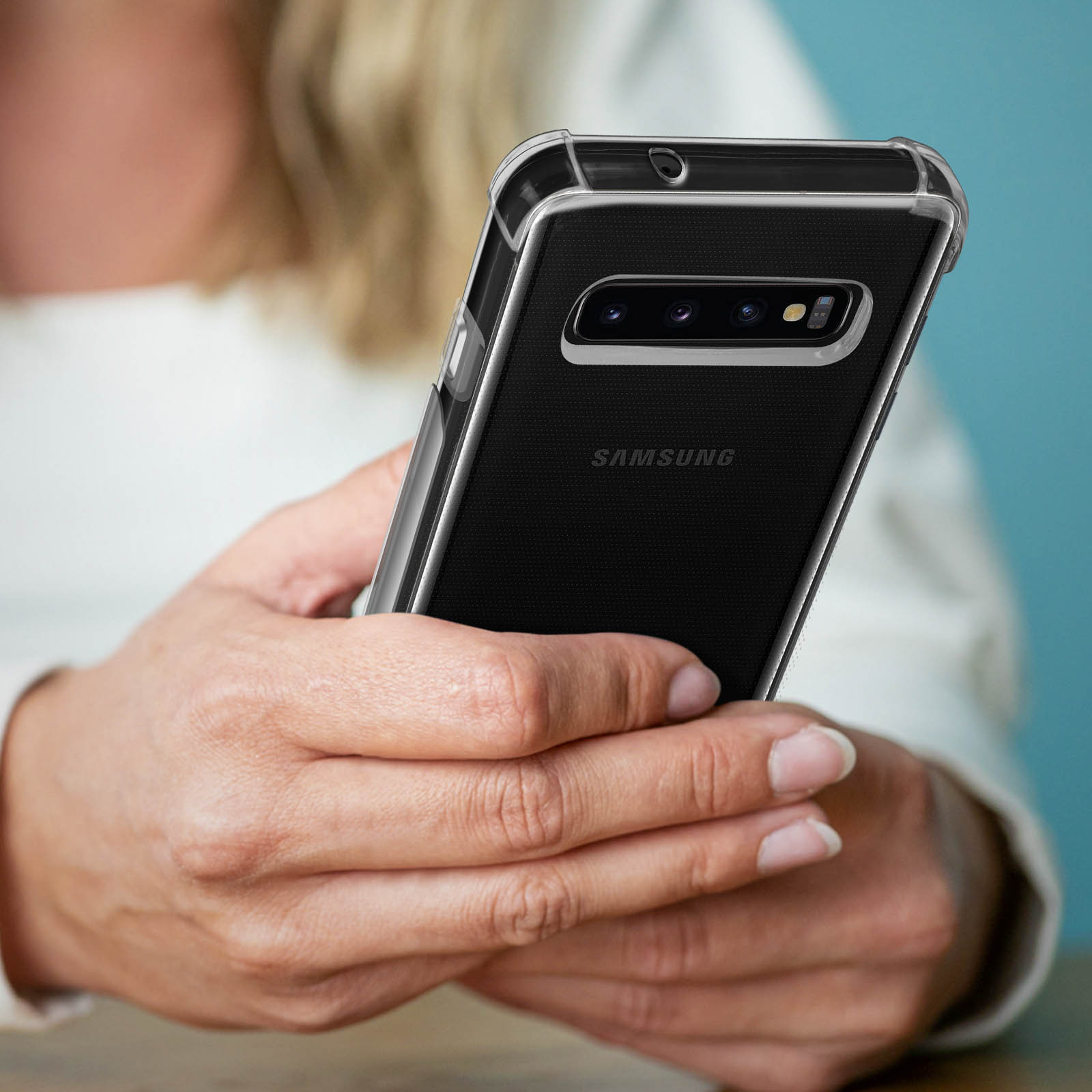 Eine Frau hält ein Telefon in einer transparenten Hülle, die Rückseite des Telefons ist sichtbar.