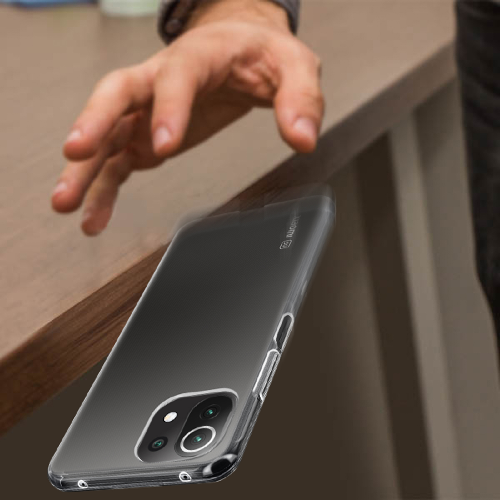 Una mano che fa cadere una custodia trasparente per telefono su un tavolo di legno.