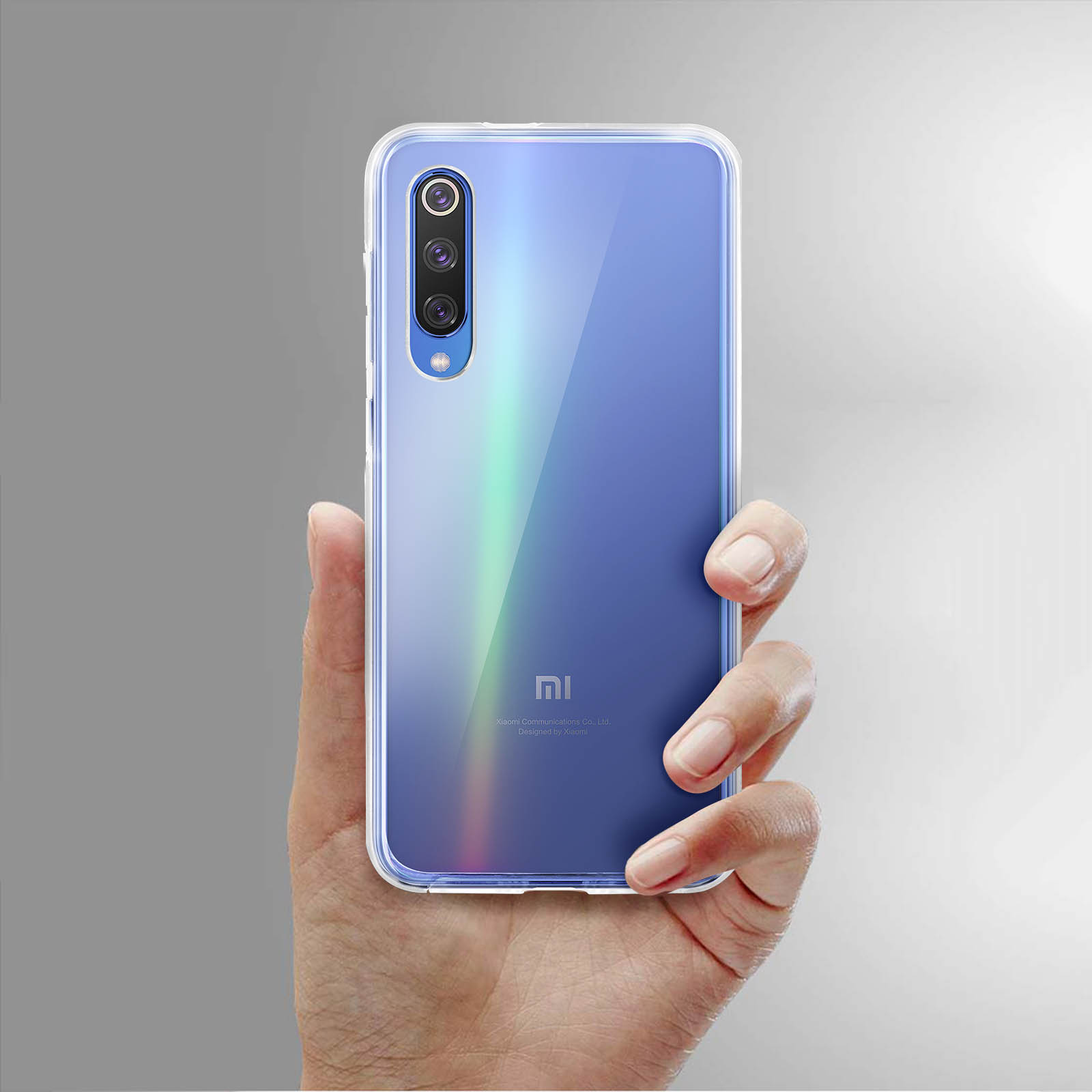 Une main tenant un téléphone dégradé bleu dans un étui transparent. Le téléphone affiche une configuration à triple caméra.