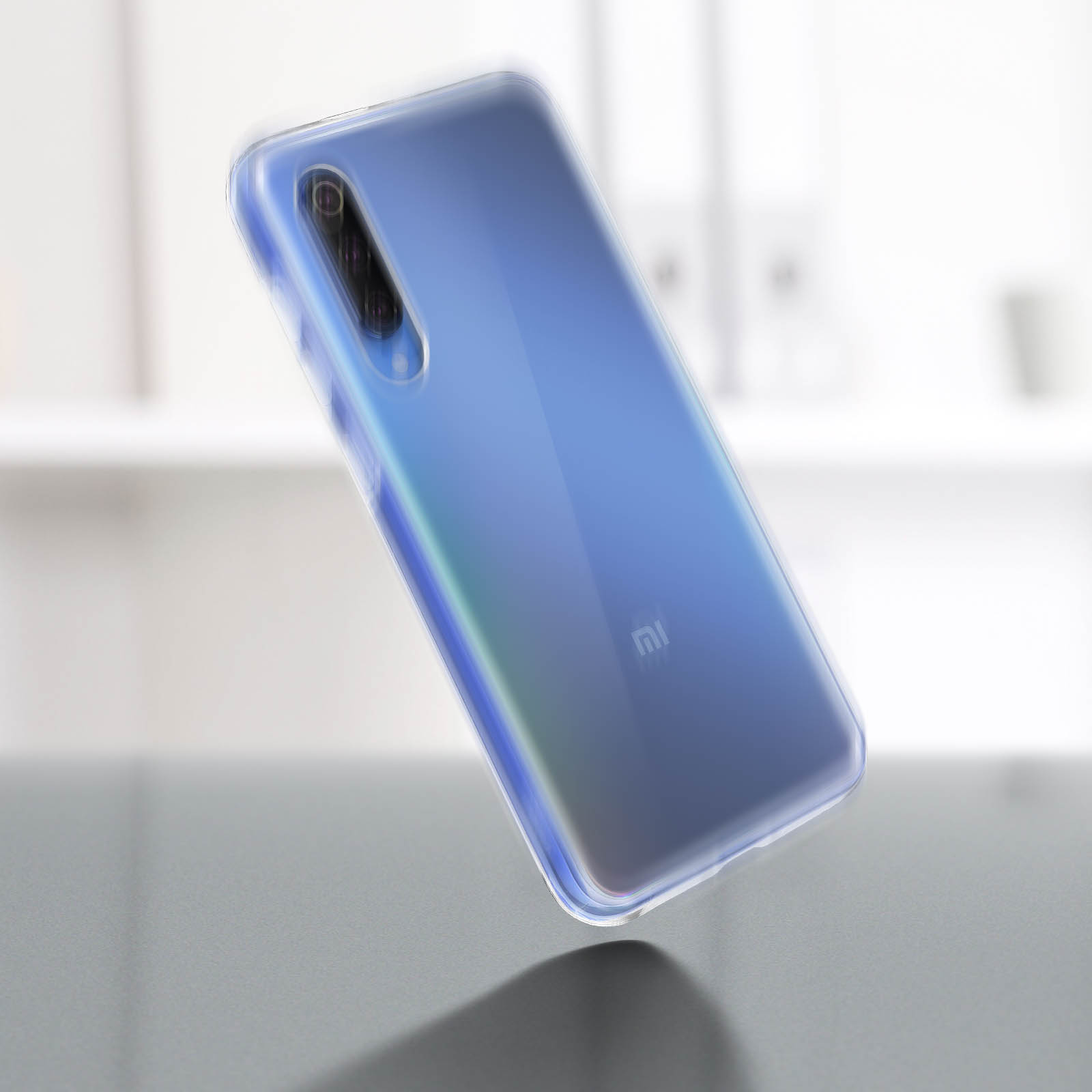 Un téléphone bleu dans une coque transparente repose sur une surface. Le téléphone a une caméra et un écran. Arrière-plan flou.