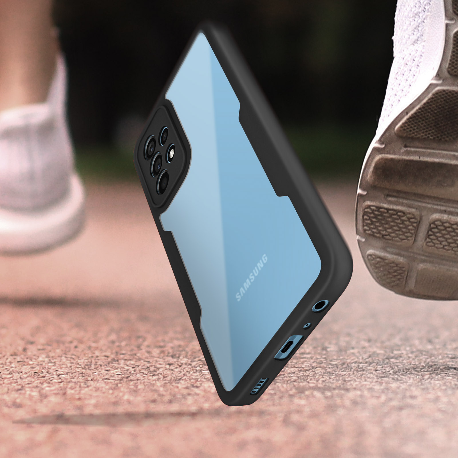 Telefoon in een hoesje, op een oppervlak in de buurt van een hardloopschoen. De case is transparant met zwarte randen.
