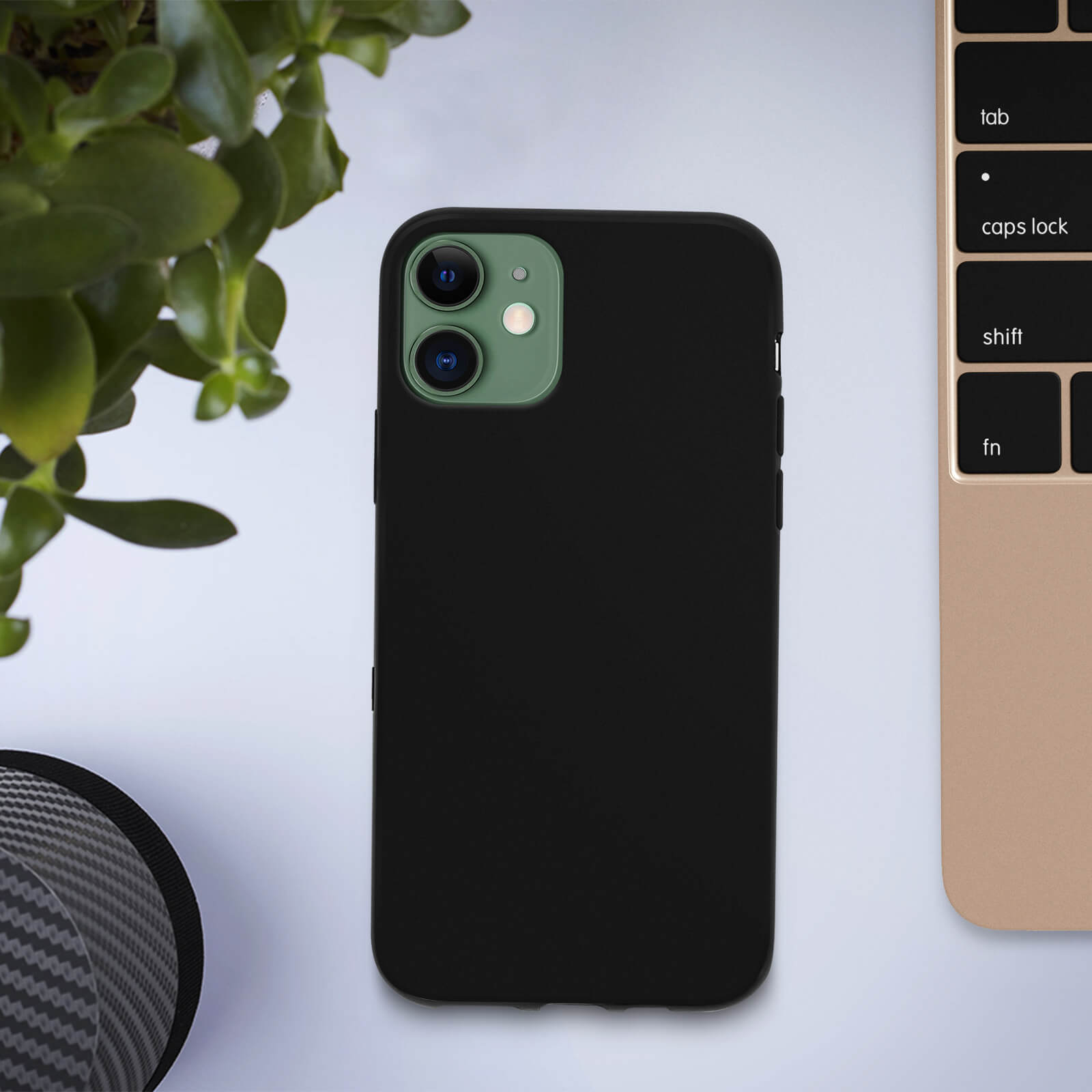 Zwarte telefoonhoes op tafel met plant en toetsenbord, groene cameralensring.