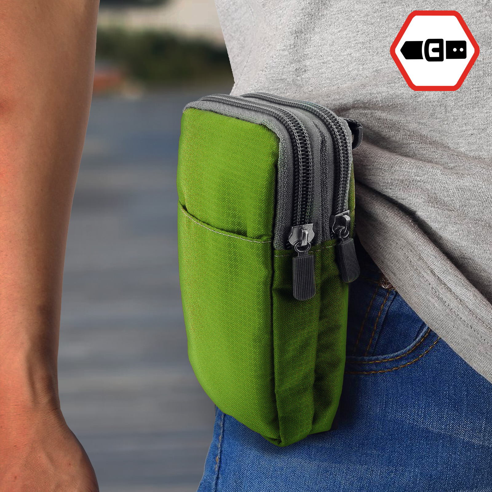 Eine Person trägt ein graues Hemd mit einer kleinen grünen Tasche am Bund. Die Tasche hat Reißverschlüsse.