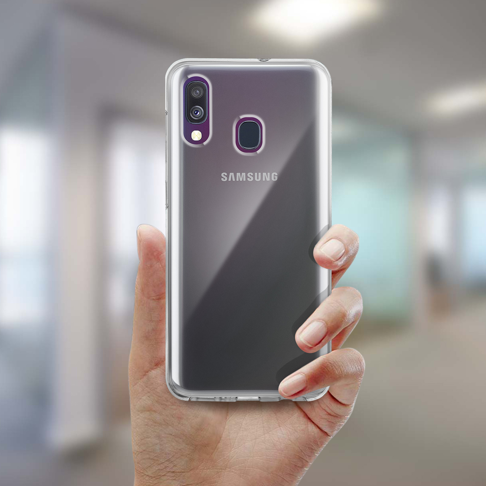 Hand die een doorzichtige telefoonhoes over een telefoon houdt. Vage achtergrond.