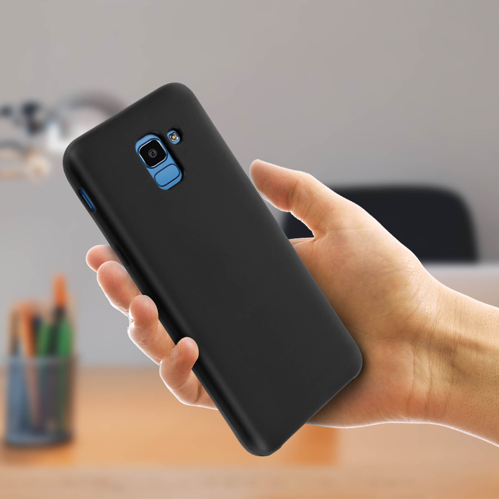 Una mano che tiene un telefono nero. Il telefono è in una custodia nera con una lente blu.