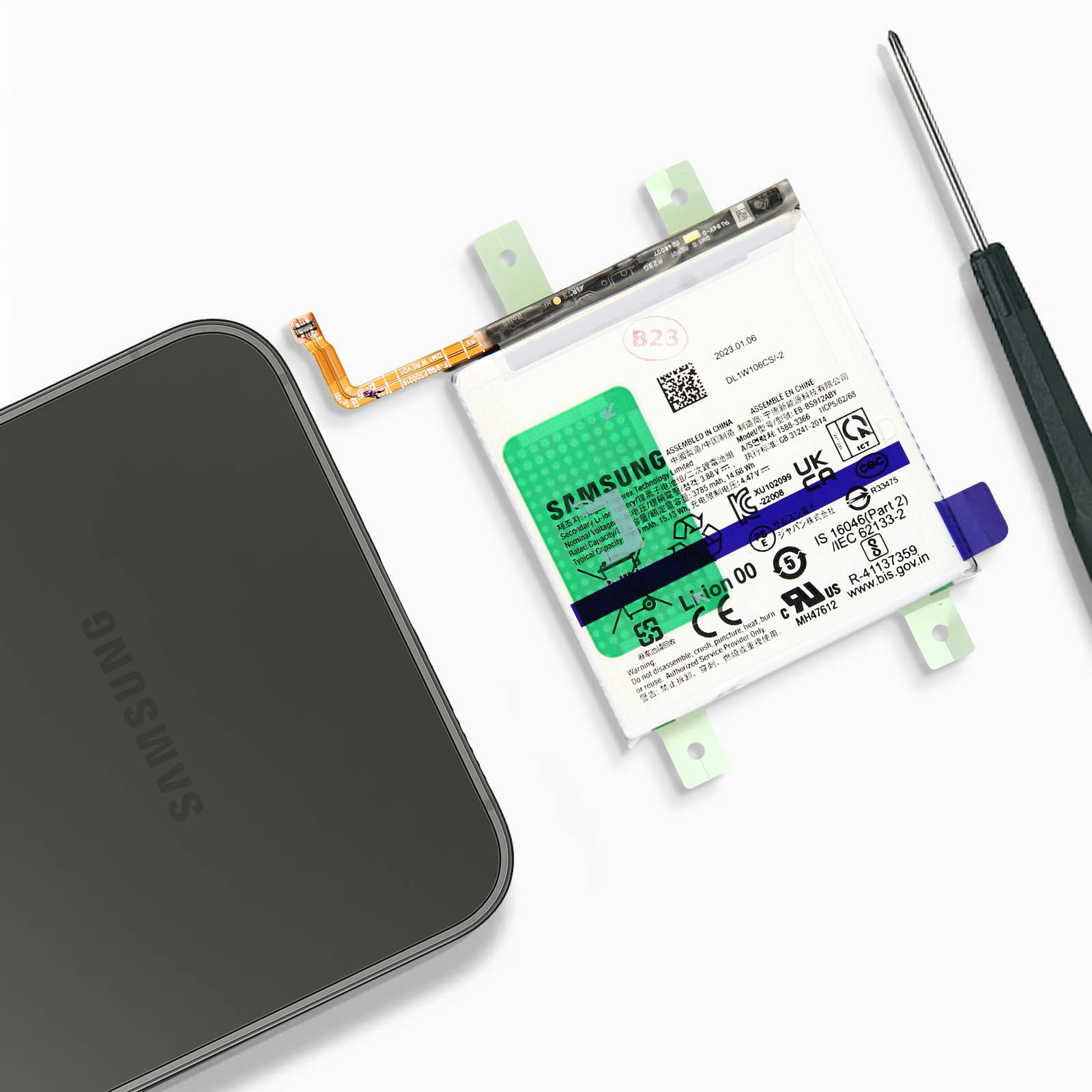 Une batterie Samsung, un appareil et un tournevis sur une surface blanche.