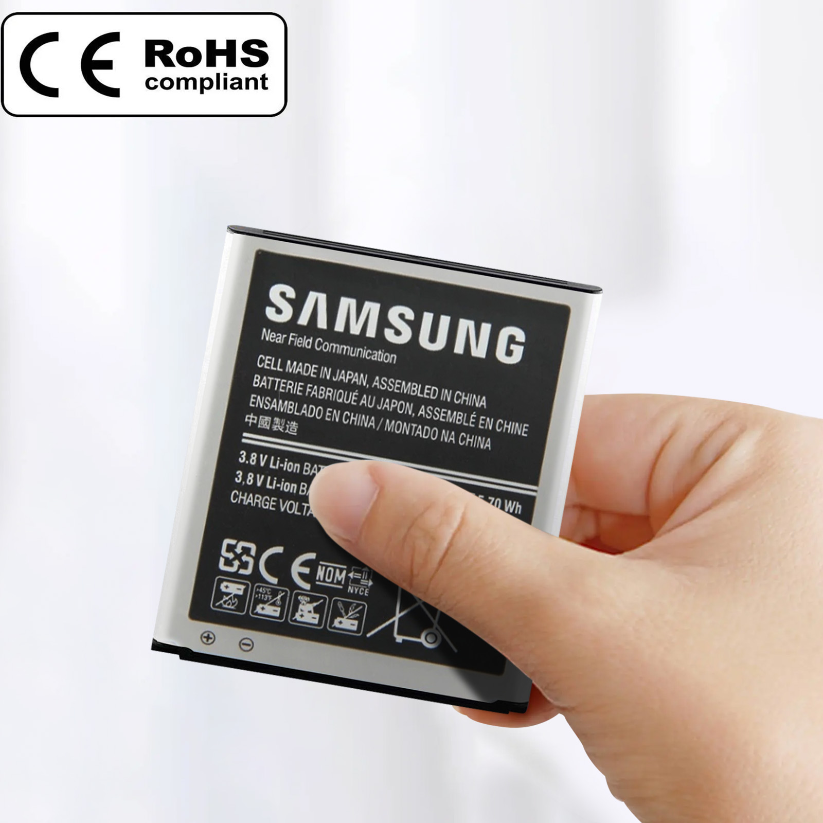 Mano sosteniendo una batería de teléfono Samsung. La batería tiene etiquetas en blanco y negro. Fondo borroso.
