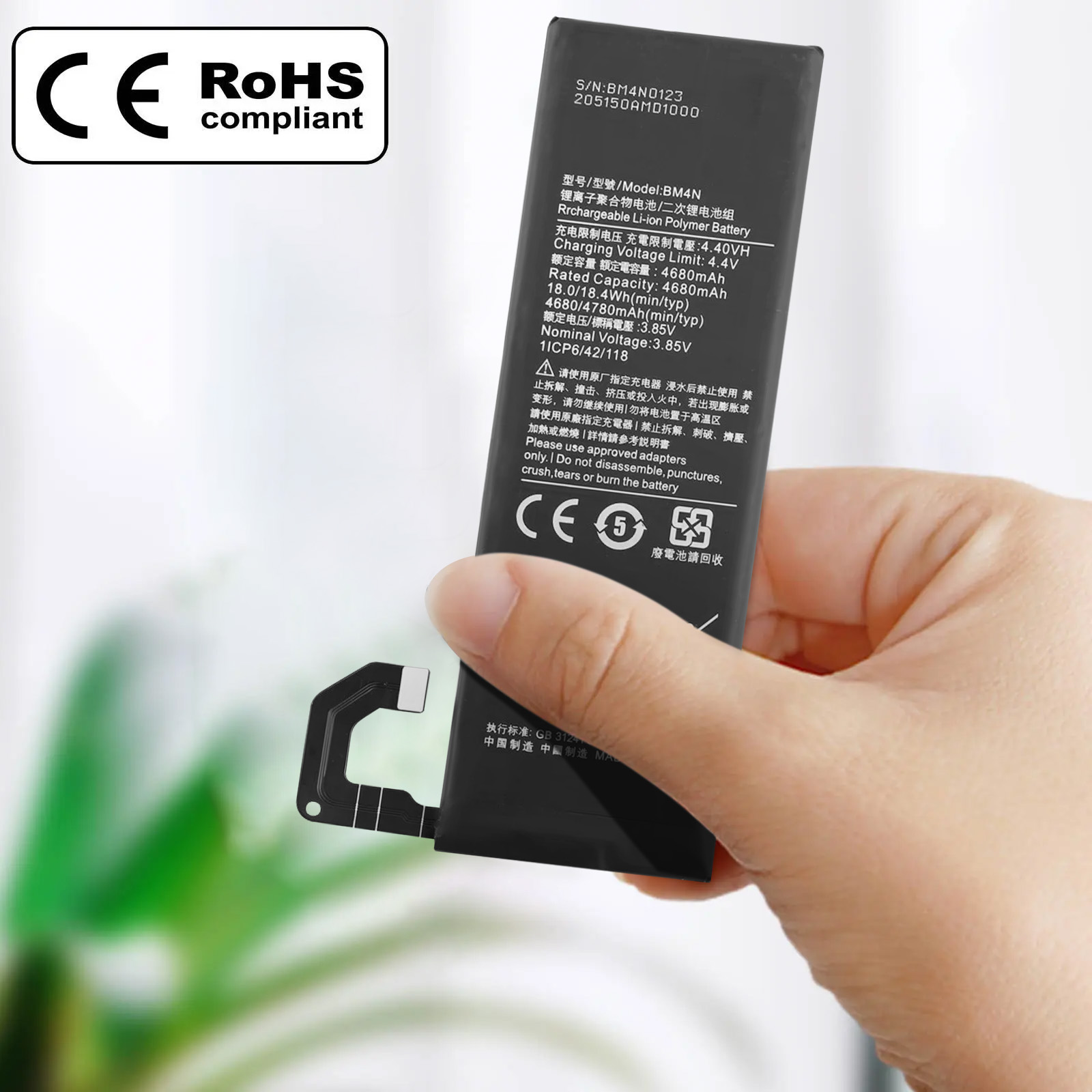 Una batería de teléfono con texto y símbolos sostenida por una mano, con marcas CE y RoHS.
