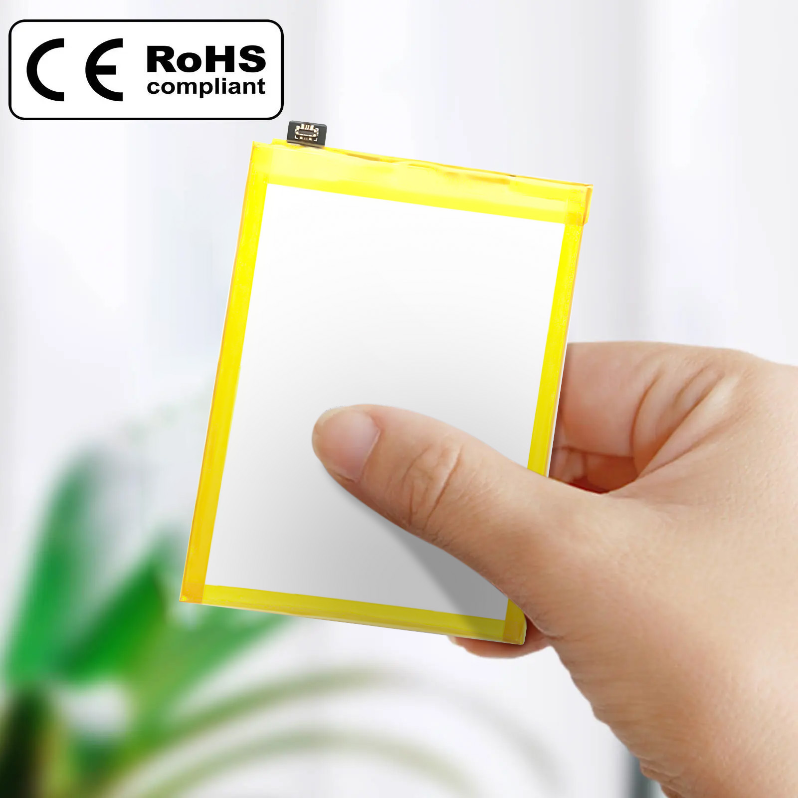 Mano sosteniendo una batería rectangular con bordes amarillos y una etiqueta ROHS conforme en blanco y negro.