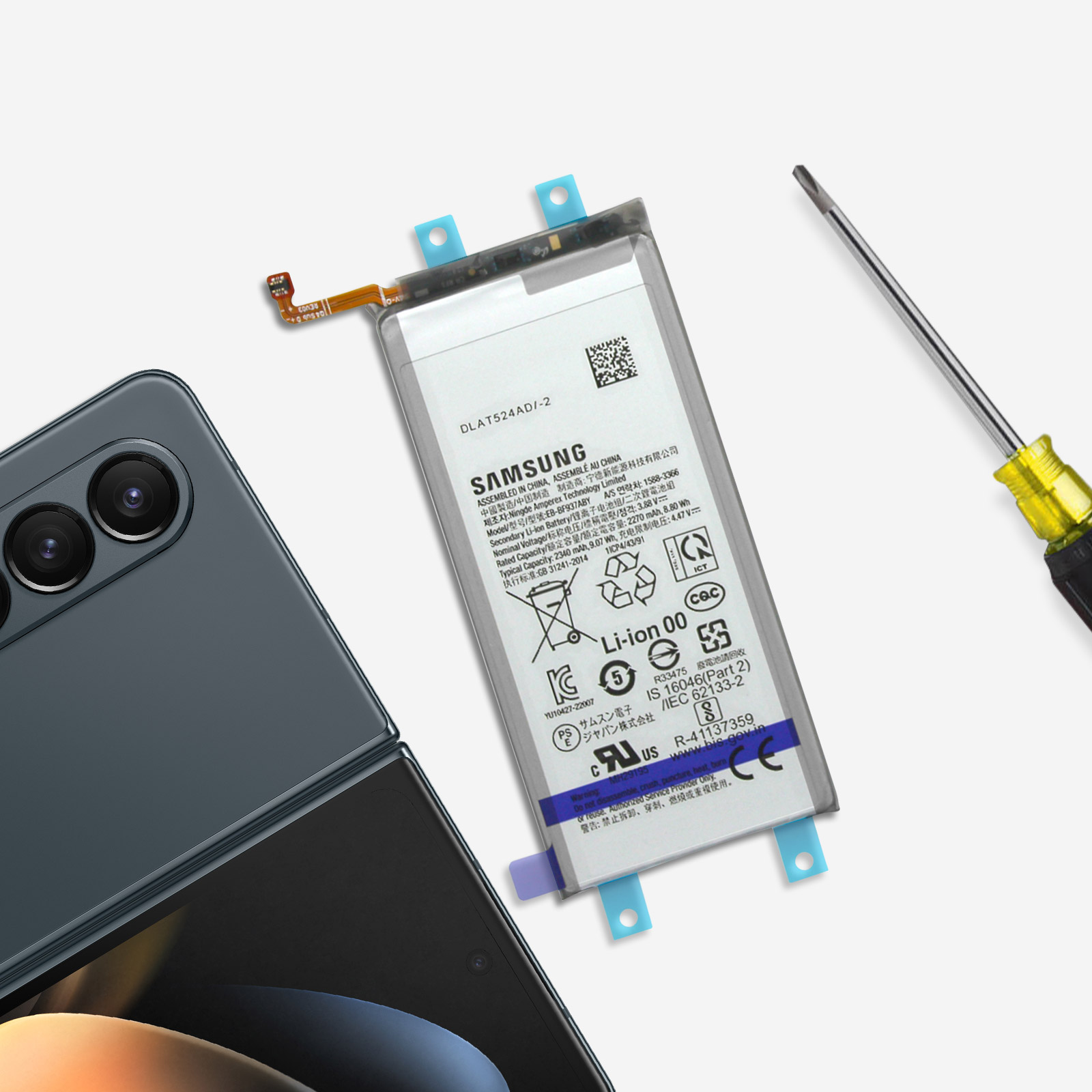 Batería de teléfono, destornillador y teléfono plegable sobre mesa. Batería con etiquetas.