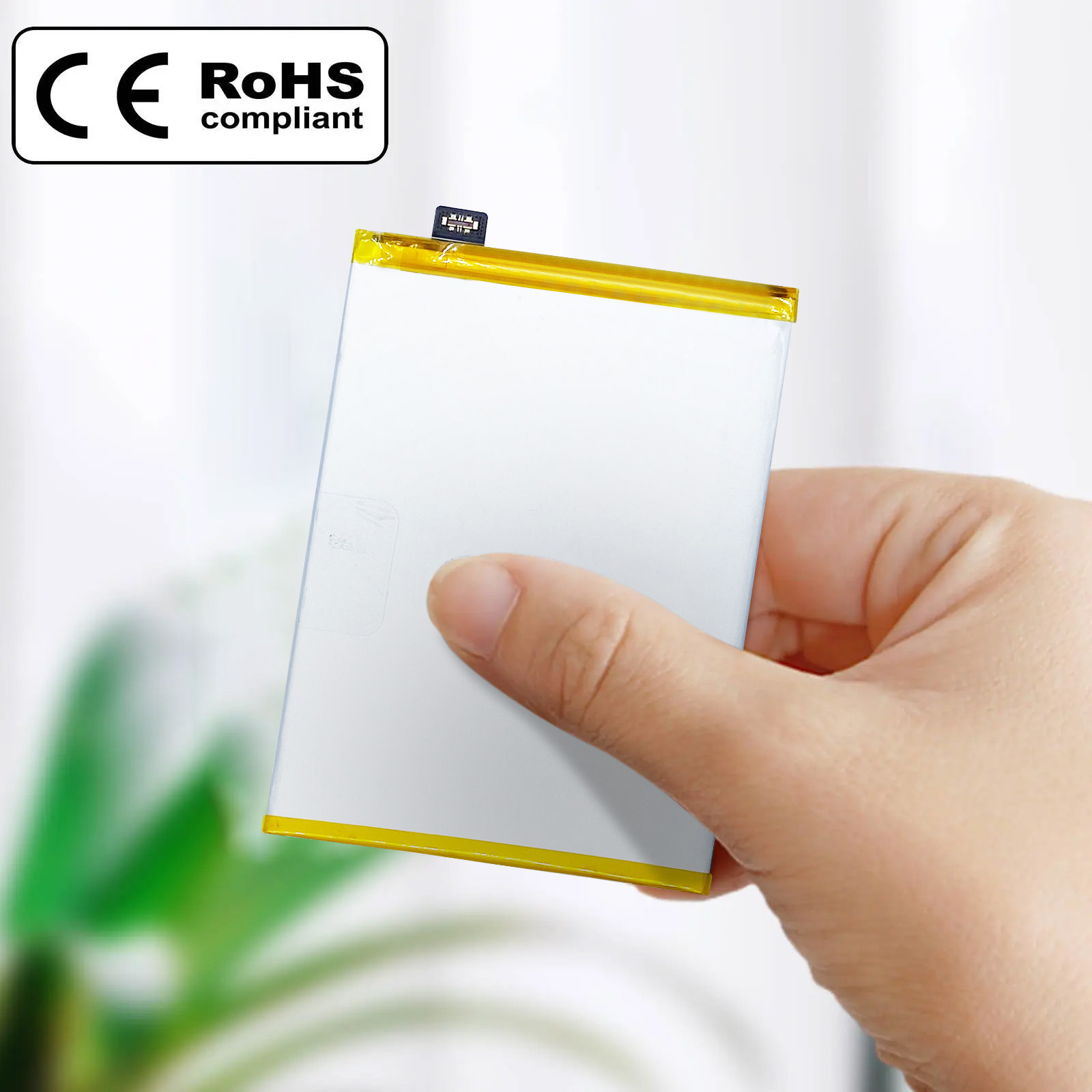Una mano sosteniendo una batería rectangular blanca y amarilla con etiquetas CE y RoHS.