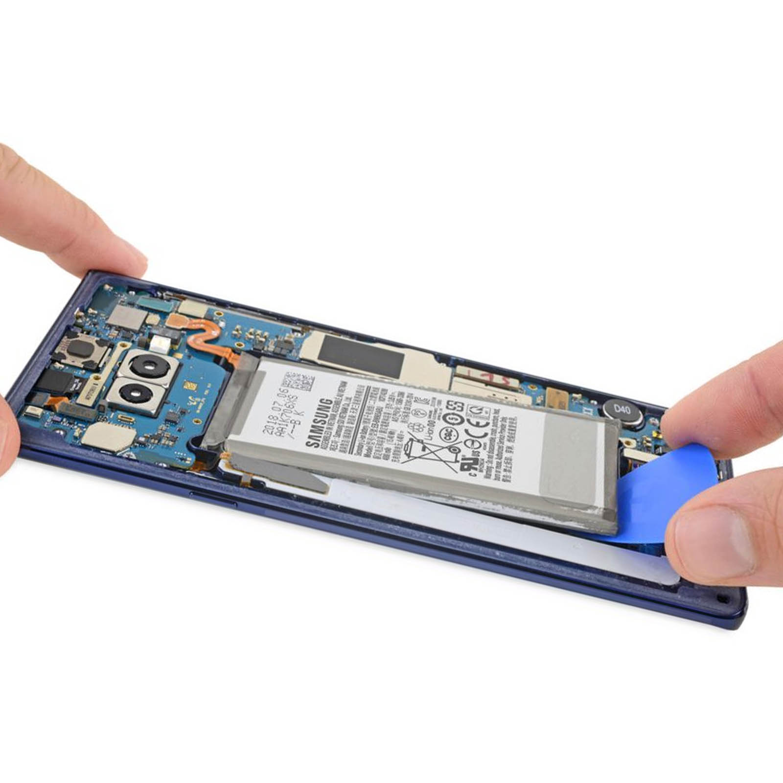 Mains tenant un téléphone avec une batterie à l'intérieur. Un outil bleu est utilisé pour retirer la batterie.