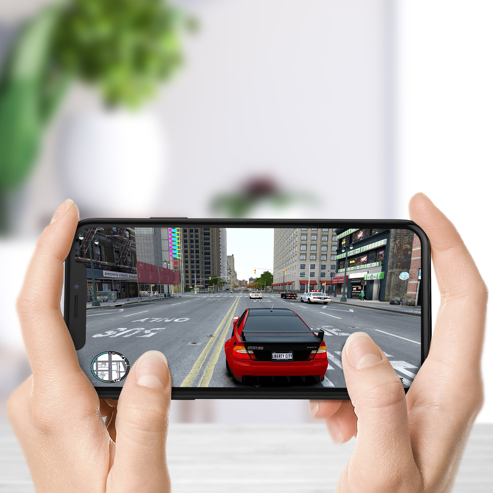 Mani che tengono un telefono che gioca a un gioco di corse automobilistiche. Lo sfondo è una strada con edifici.