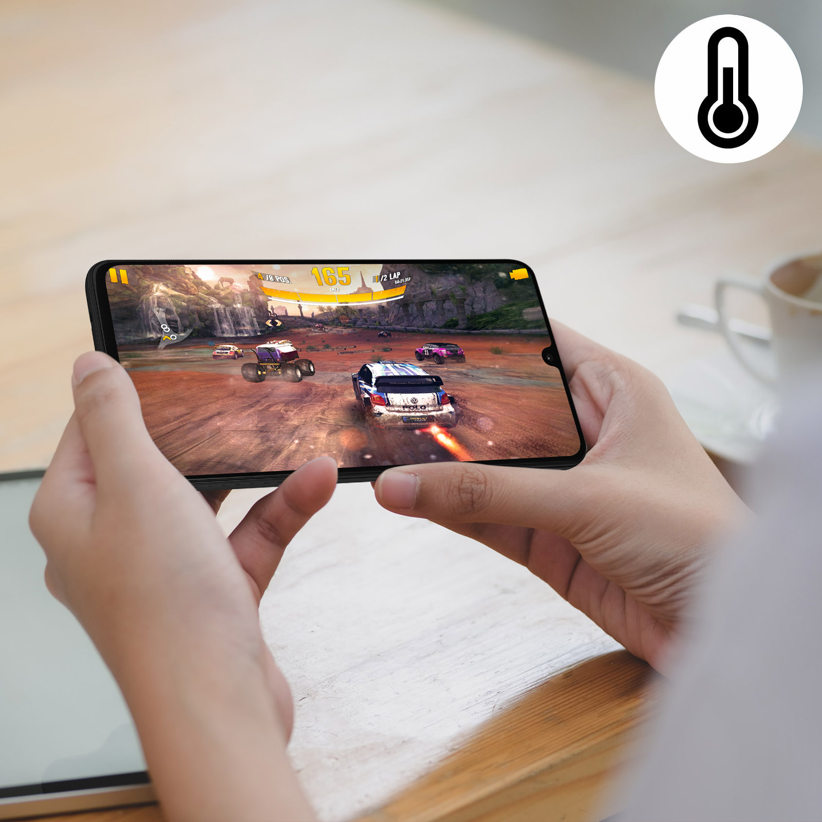 Des mains tiennent un téléphone jouant à un jeu de course. Une icône de température en haut à droite.