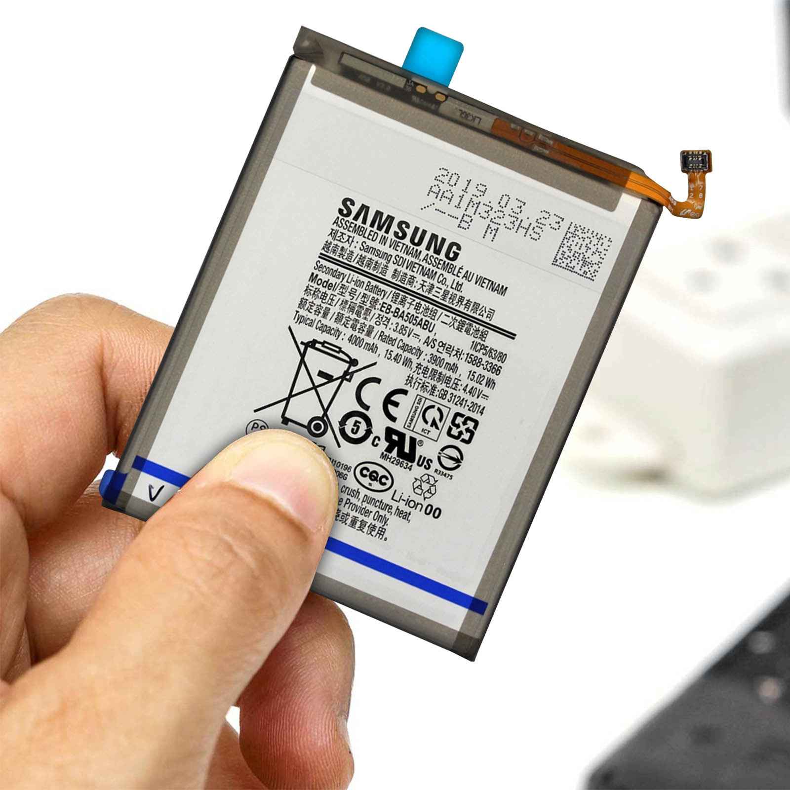 Une personne tenant une batterie de téléphone avec du texte. La batterie est blanche avec un cadre noir.
