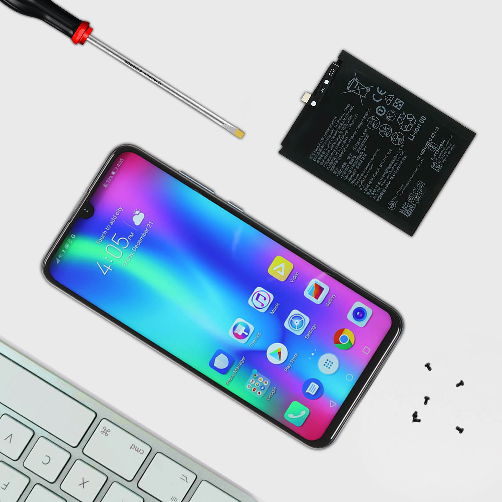 Un telefono, una batteria, una tastiera e un cacciavite sono su una superficie bianca.