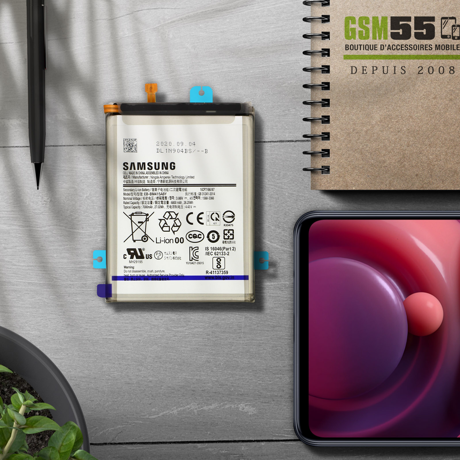 Una batteria del telefono con testo e codici. È su una scrivania con altri accessori sullo sfondo.