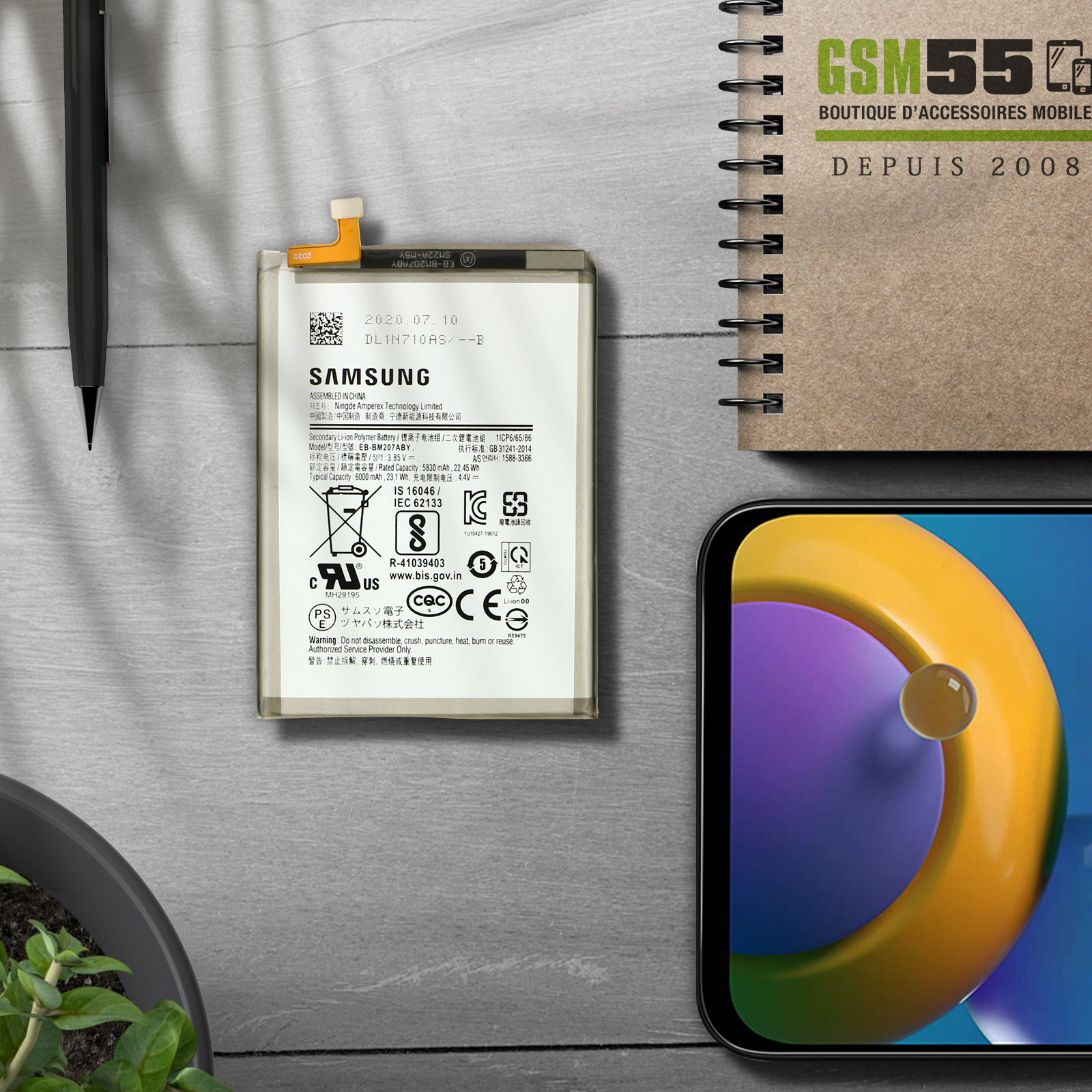 Batterie de téléphone avec étiquettes, stylo, carnet et téléphone avec image jaune et orange.