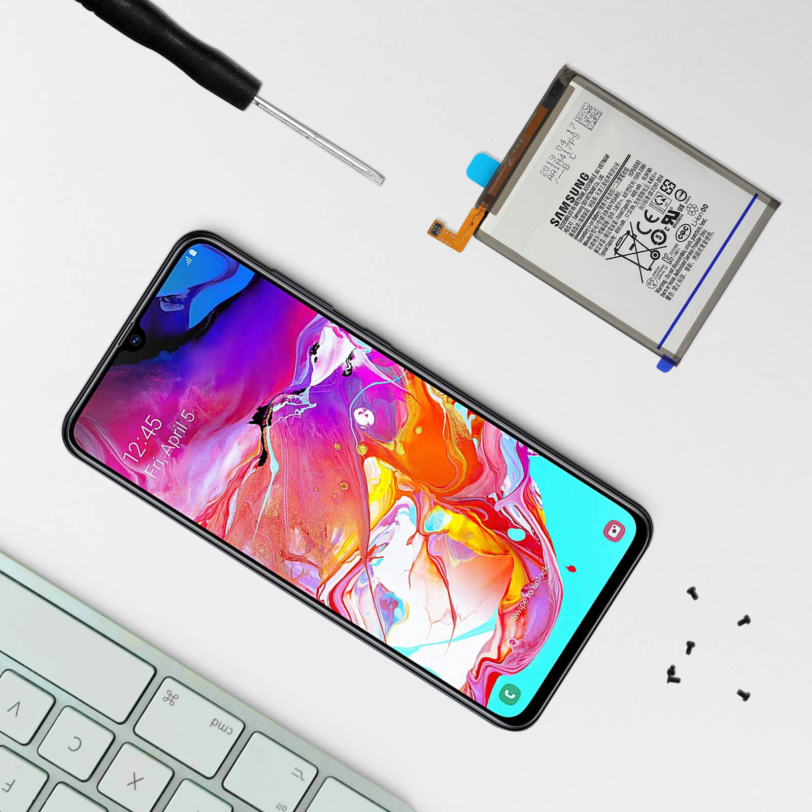 Ein Telefon, ein Schraubendreher und eine Tastatur. Der Hintergrund ist weiß.