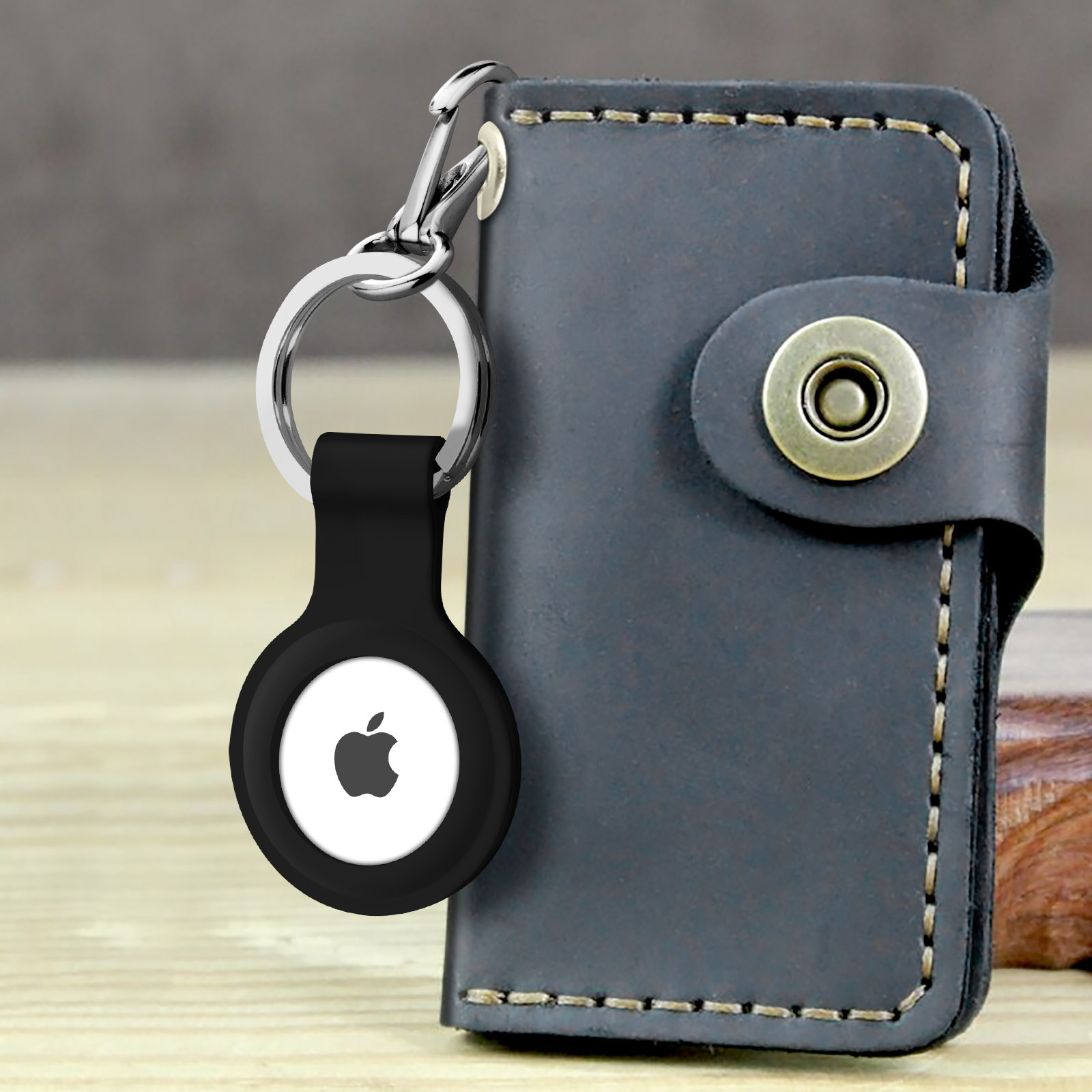AirTag nero con logo Apple attaccato a un portachiavi in pelle nera.