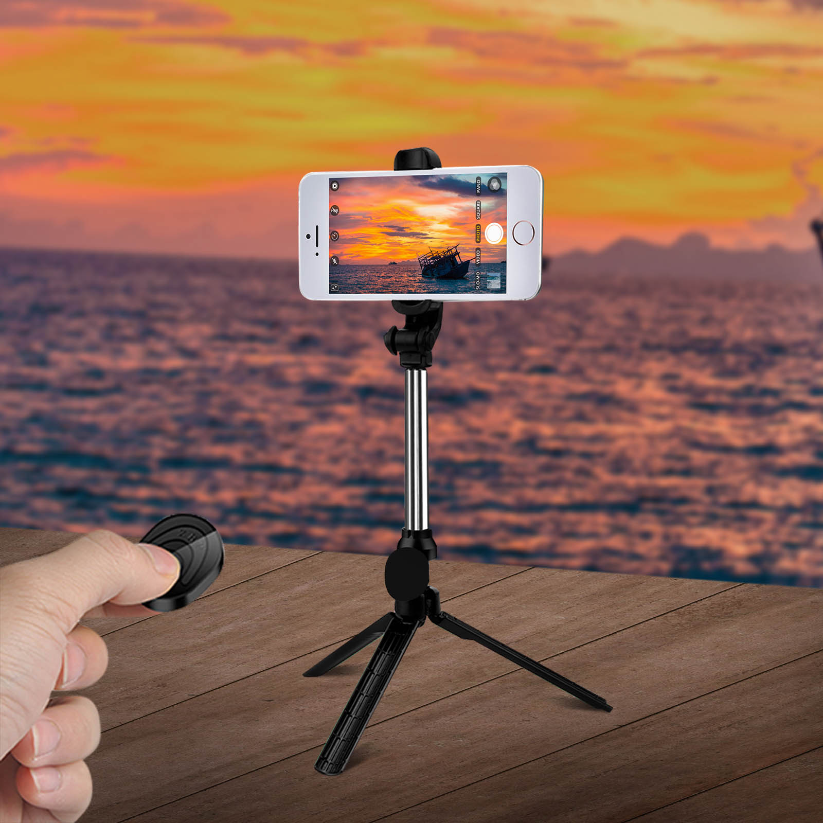 Ein Telefon auf einem Stativ mit Fernbedienung vor einem Sonnenuntergang mit einem Boot.