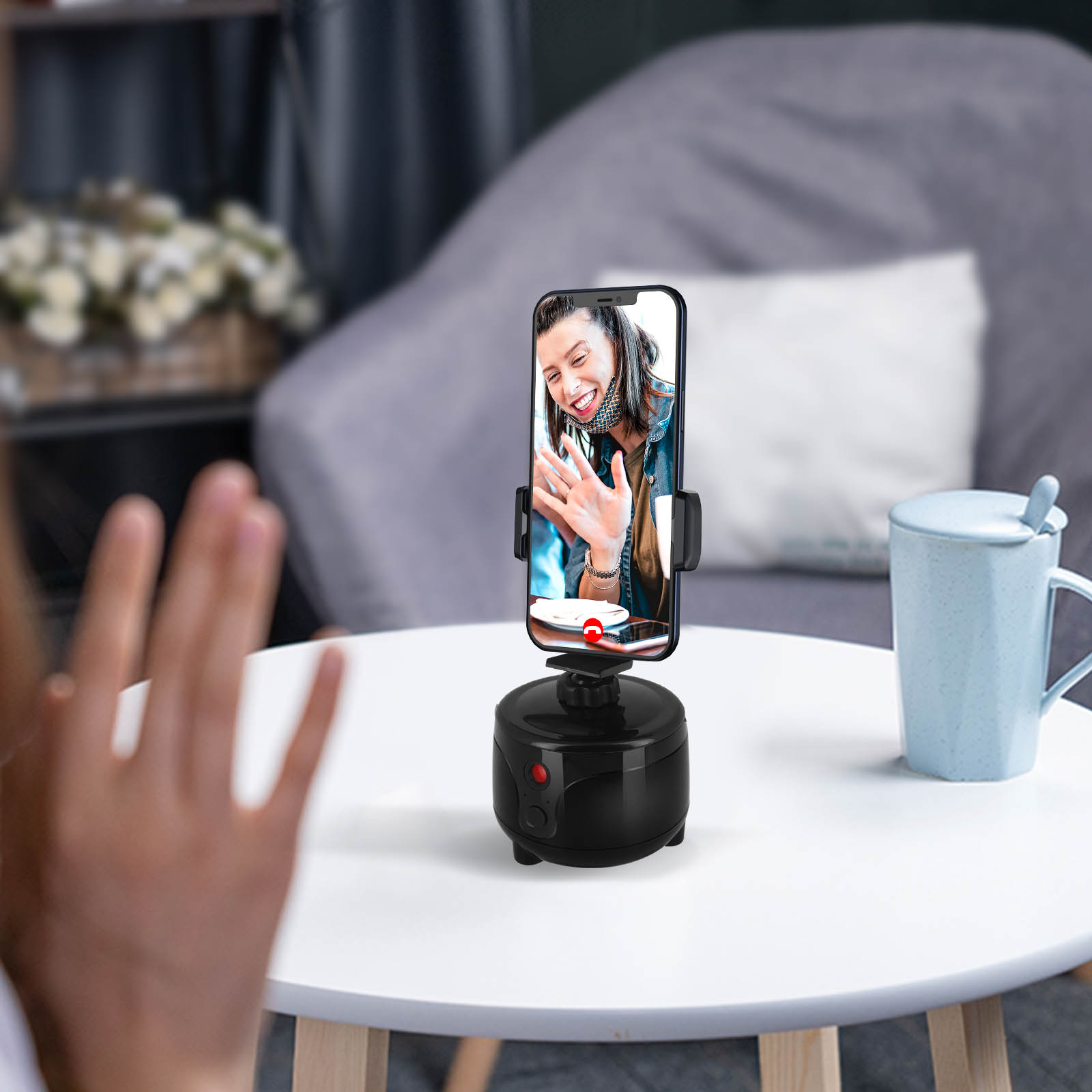 Person winkt Telefon, das an drehbarem Ständer befestigt ist. Telefon zeigt Person im Anruf.