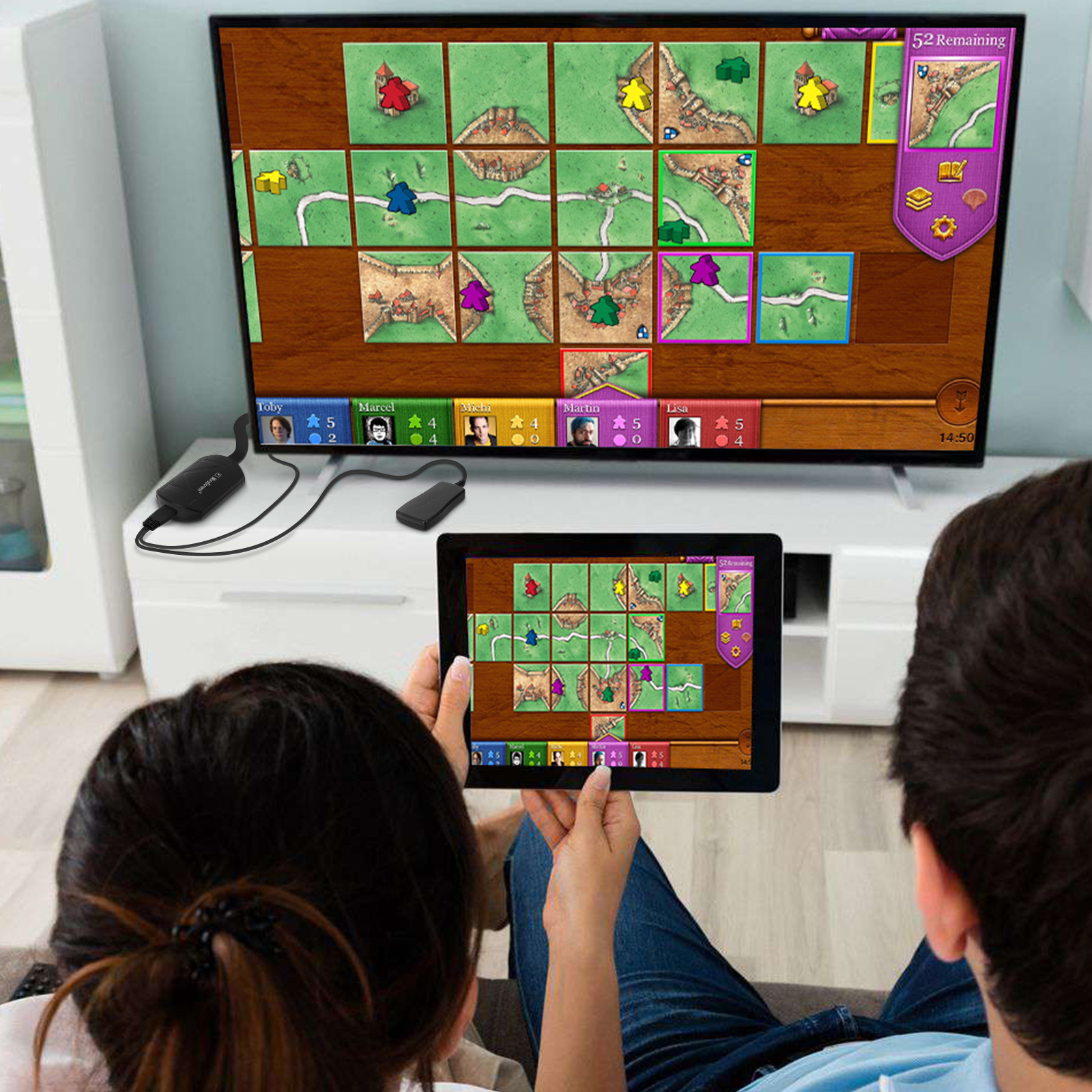 Persone che giocano a un gioco da tavolo su una TV e un tablet. Il tabellone è visibile su entrambi gli schermi.