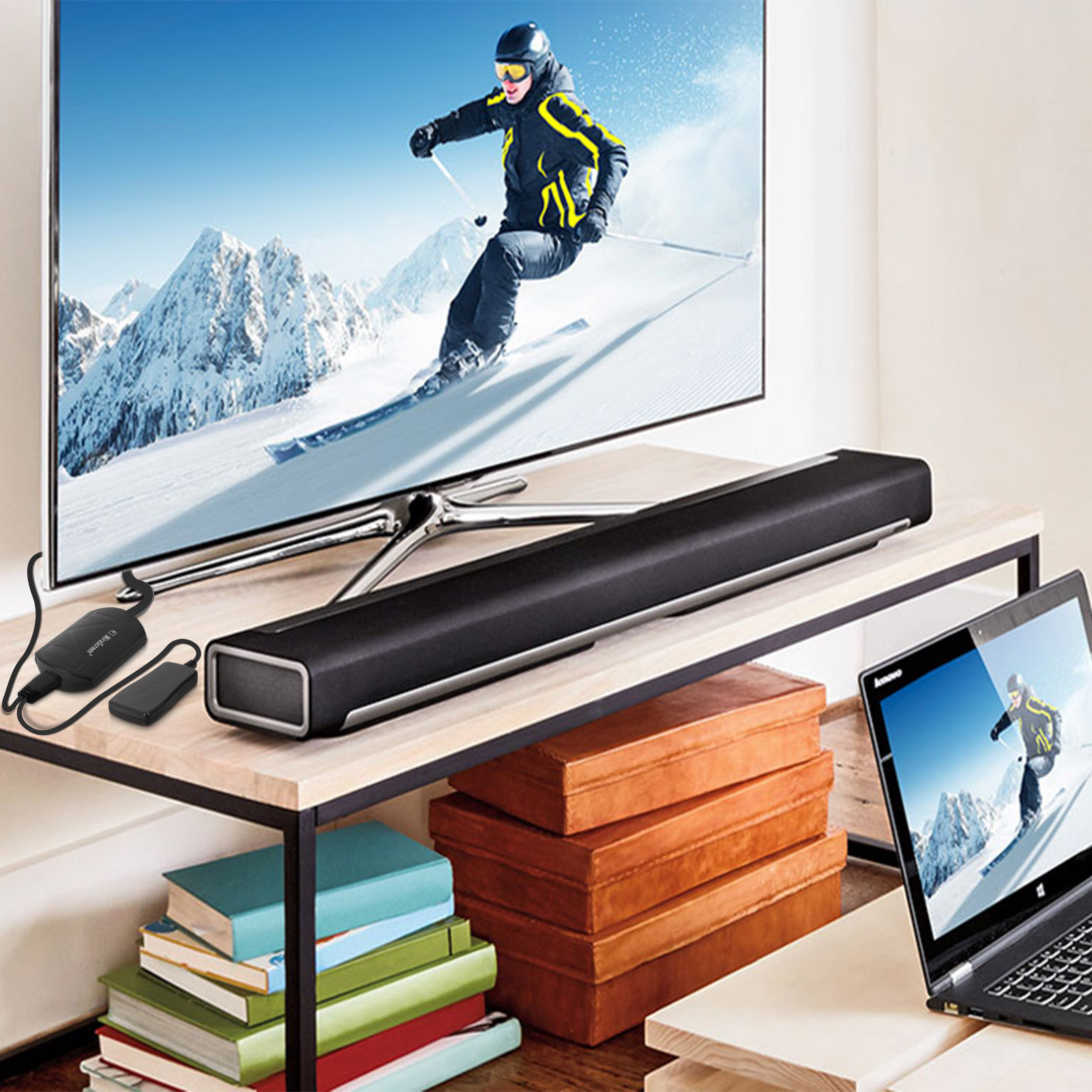 TV su un tavolo con una soundbar. Un laptop e un piccolo dispositivo sono anche sul tavolo.