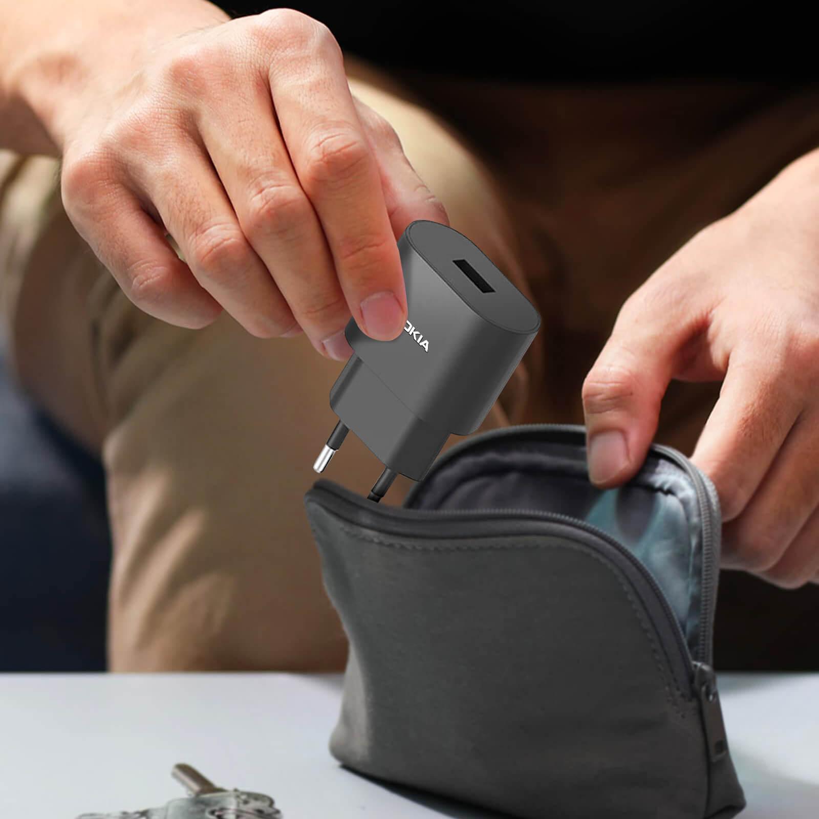 Une main met un chargeur sombre dans une petite pochette. Le chargeur a un logo Nokia.