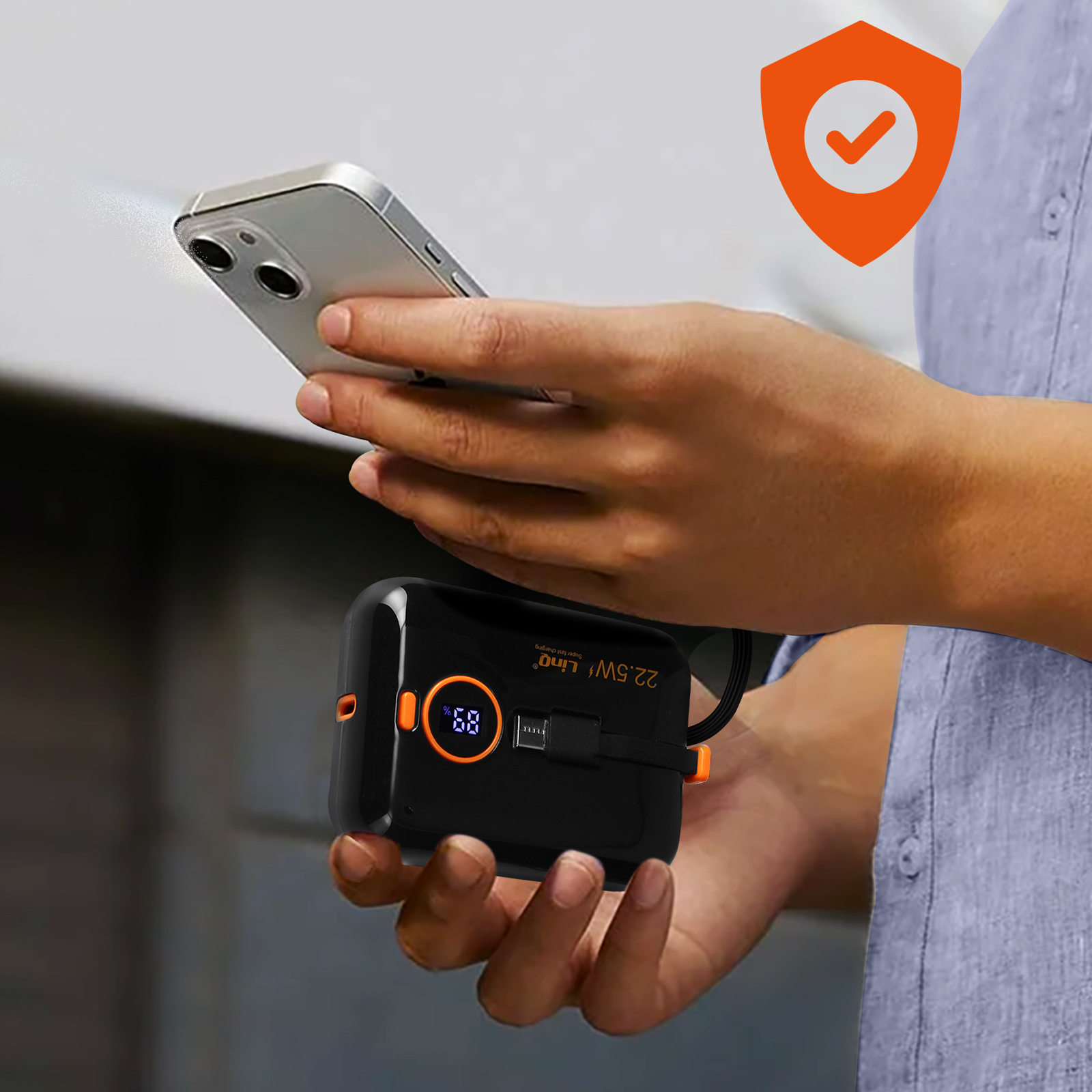 Una persona tiene in mano uno smartphone e un power bank nero con interfaccia arancione.