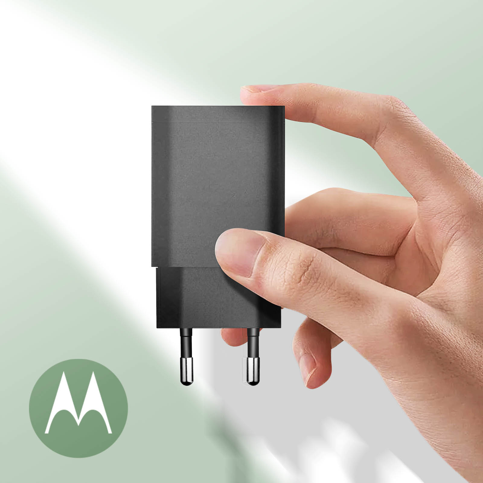 Un caricabatterie nero tenuto in mano, con un logo Motorola sul lato sinistro, su un cerchio verde.