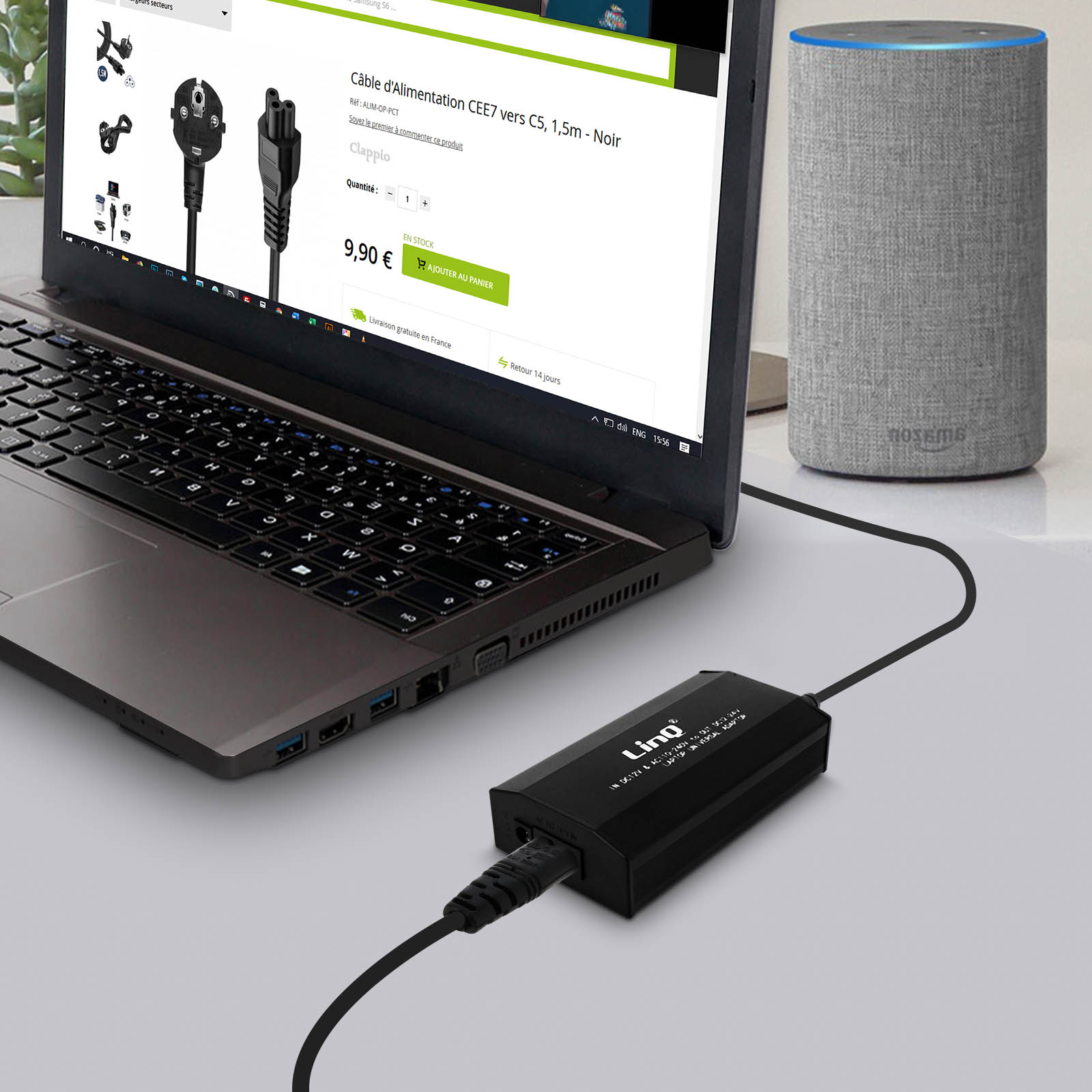 Una laptop conectada a un altavoz Alexa. Un cable de alimentación está conectado a un adaptador negro y a la laptop.