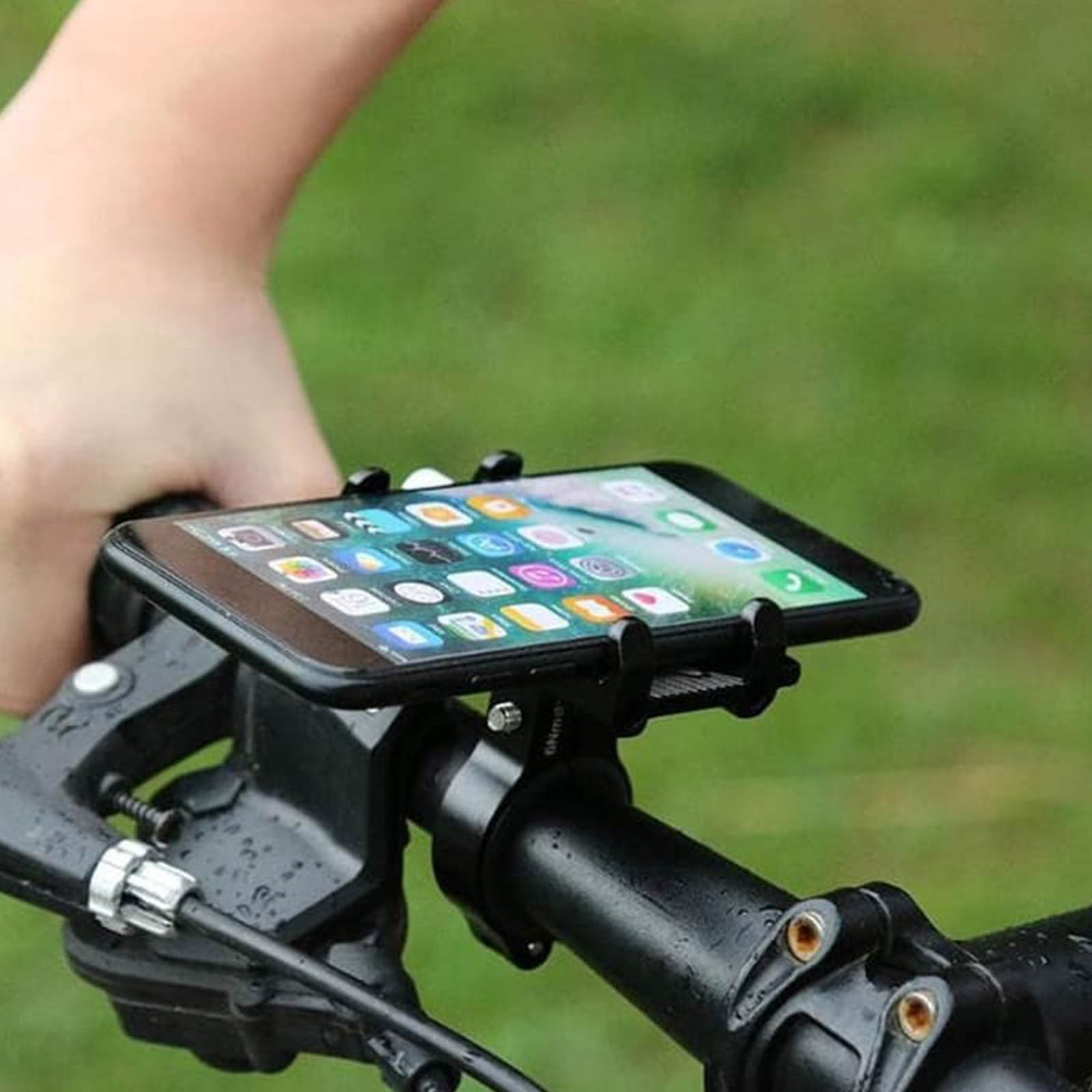 Smartphone an einem Fahrradlenker montiert, grüner verschwommener Hintergrund.