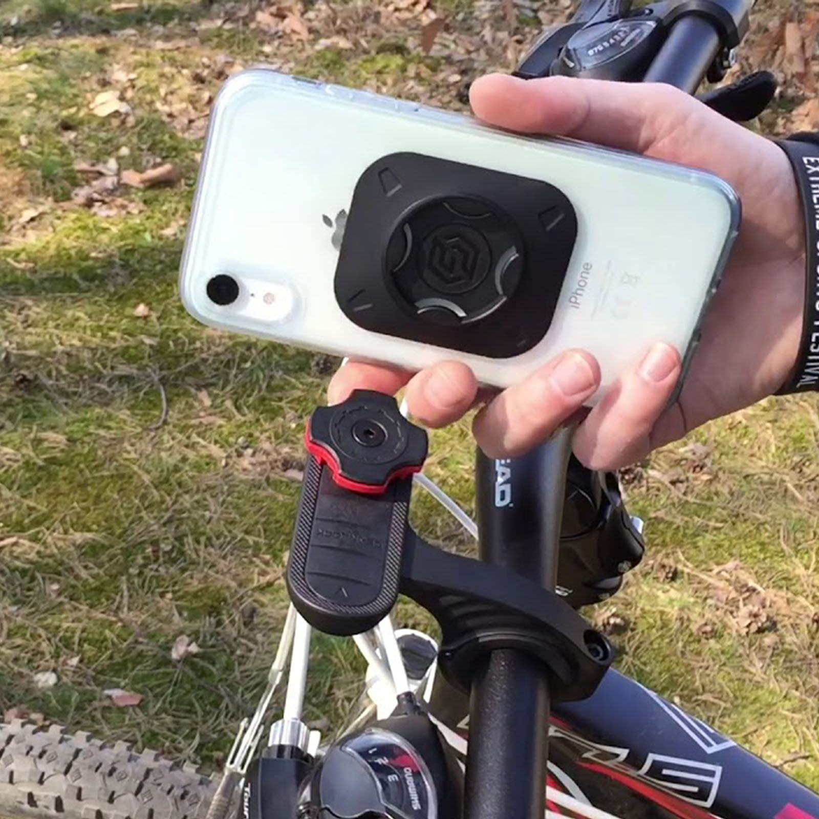 Persona sosteniendo un teléfono con un soporte para bicicleta en el manillar.