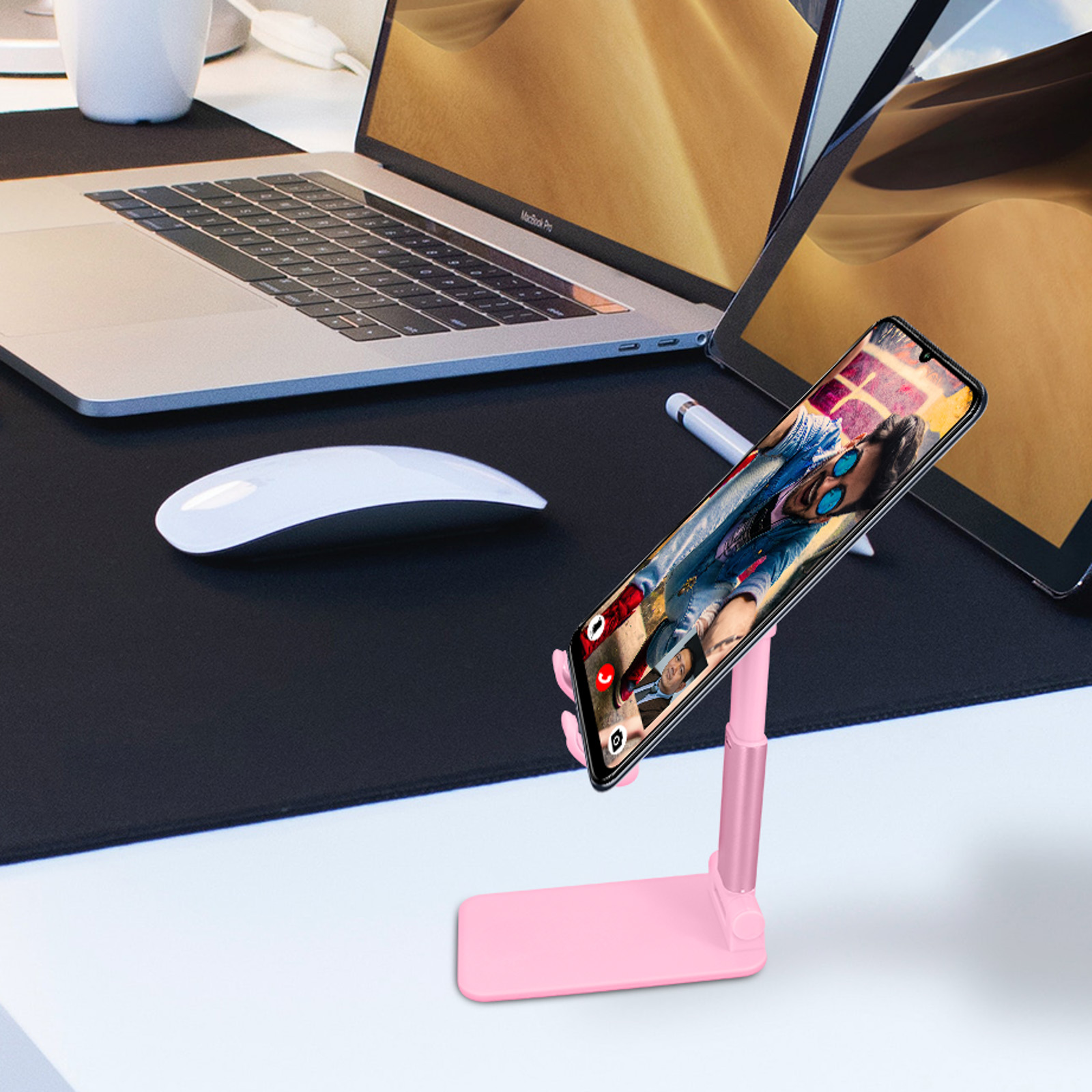 Un téléphone est sur un support rose, affichant une photo. Il y a un ordinateur portable et une tablette en arrière-plan.