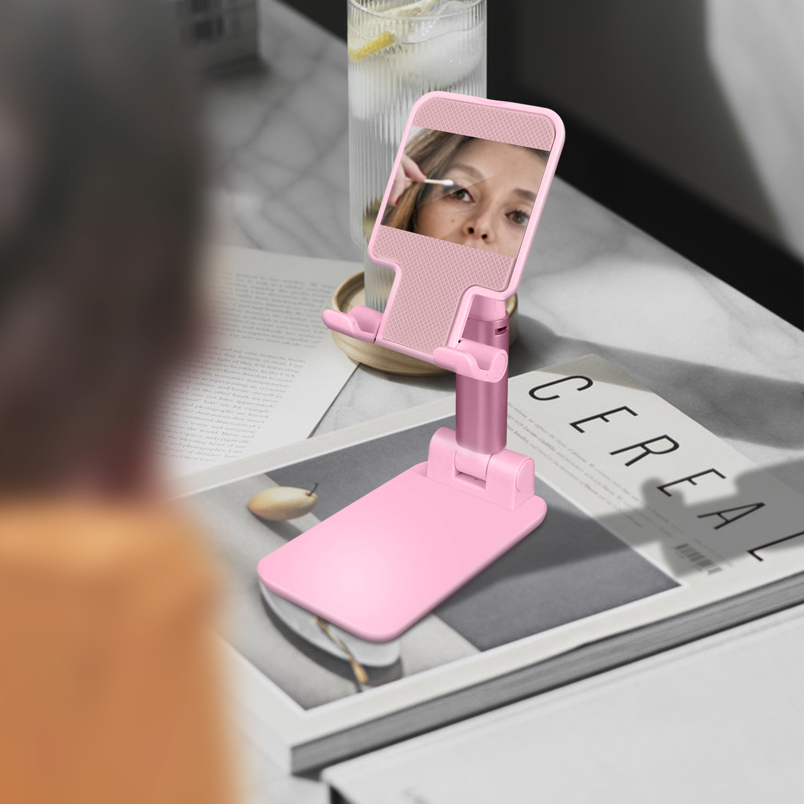 Support de téléphone avec miroir et personne qui le regarde ; boîte de céréales en arrière-plan.