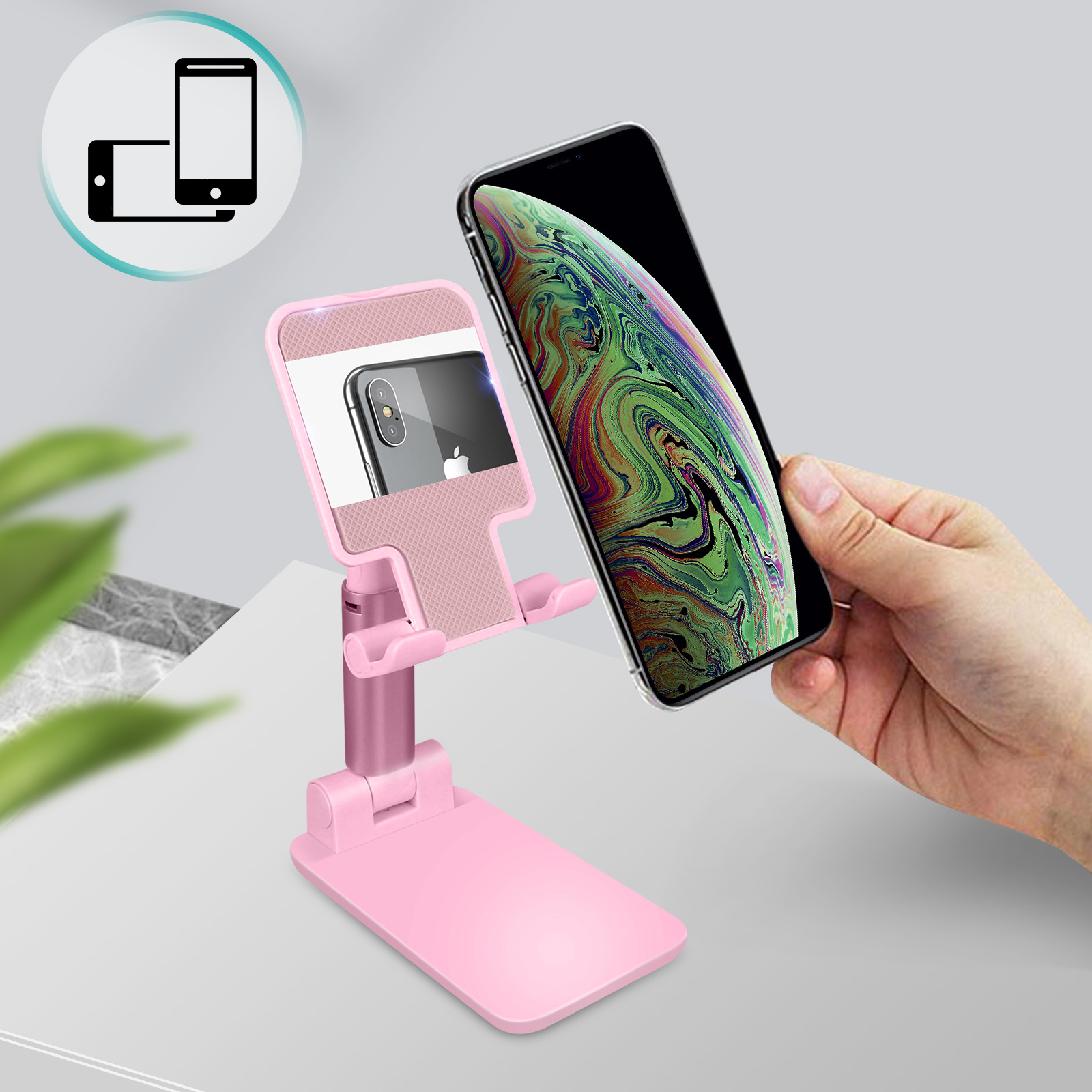 Rosa Telefonständer mit einem Telefon darin. Eine Hand hält im Hintergrund ein Telefon.