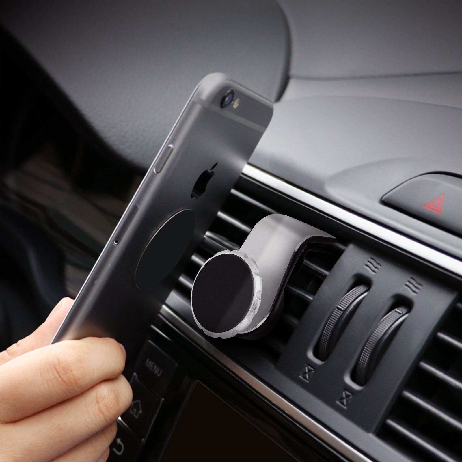 Eine Hand platziert ein Telefon auf einer magnetischen Autotelefonhalterung. Autolüftung und Armaturenbrett im Hintergrund.