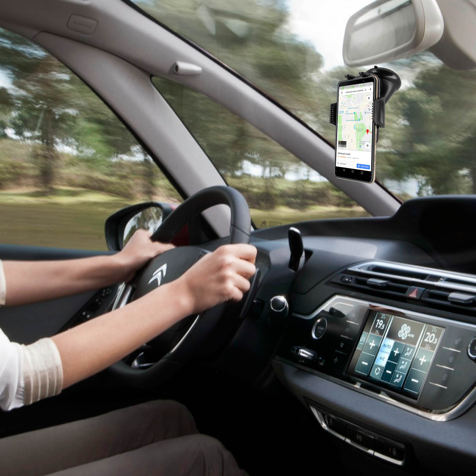Eine Person fährt ein Auto. Ein Telefon mit Karte ist an der Windschutzscheibe montiert.